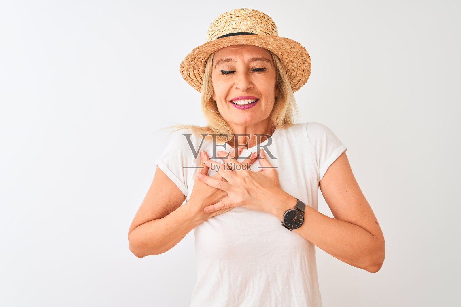 中年妇女穿着休闲t恤和帽子站在孤立的白色背景微笑，双手放在胸前，闭上眼睛和感激的手势在脸上。健康的概念。照片摄影图片