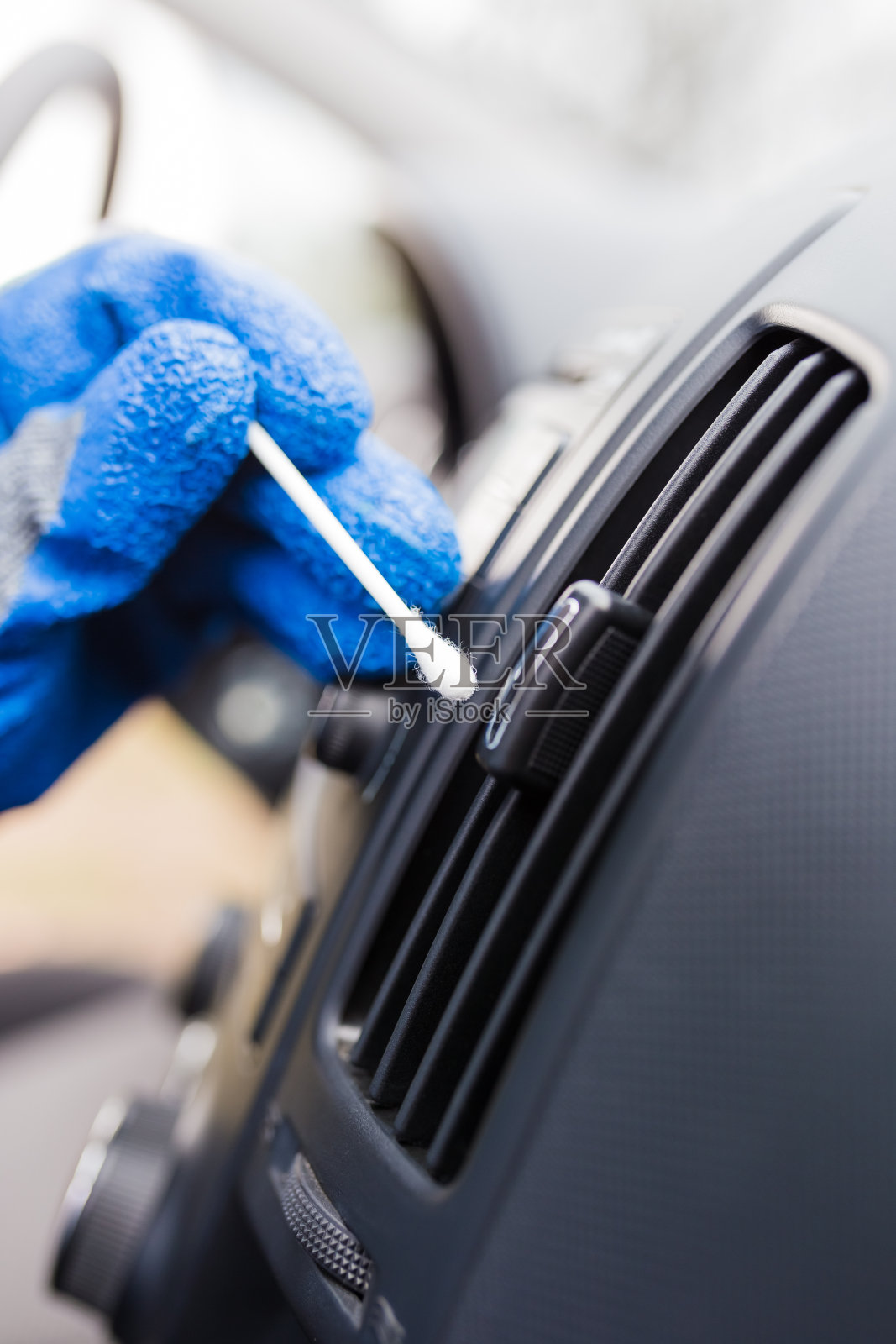 用棉签擦拭手动清洁汽车空调排气格栅。照片摄影图片