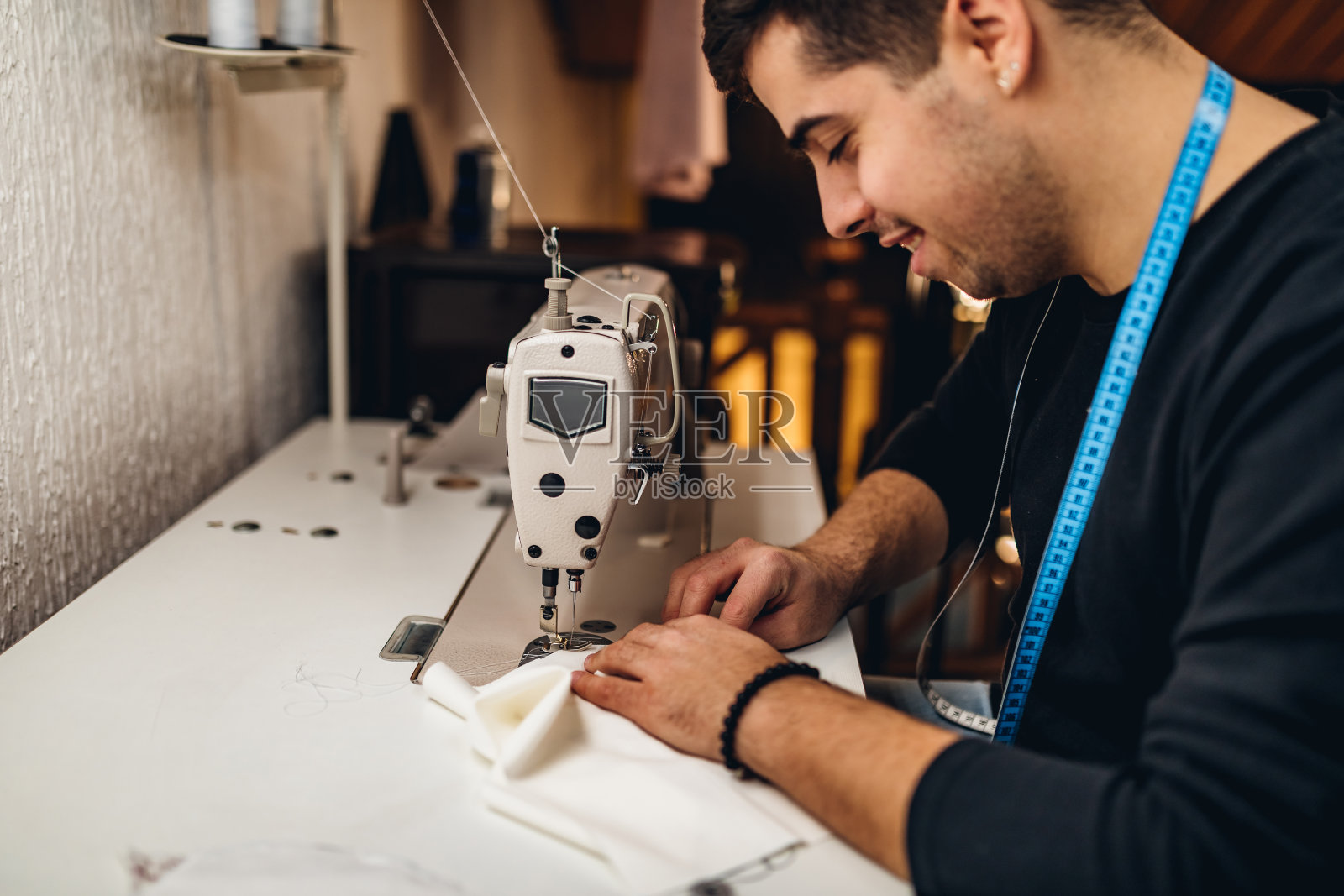年轻的男裁缝与缝纫机工作照片摄影图片