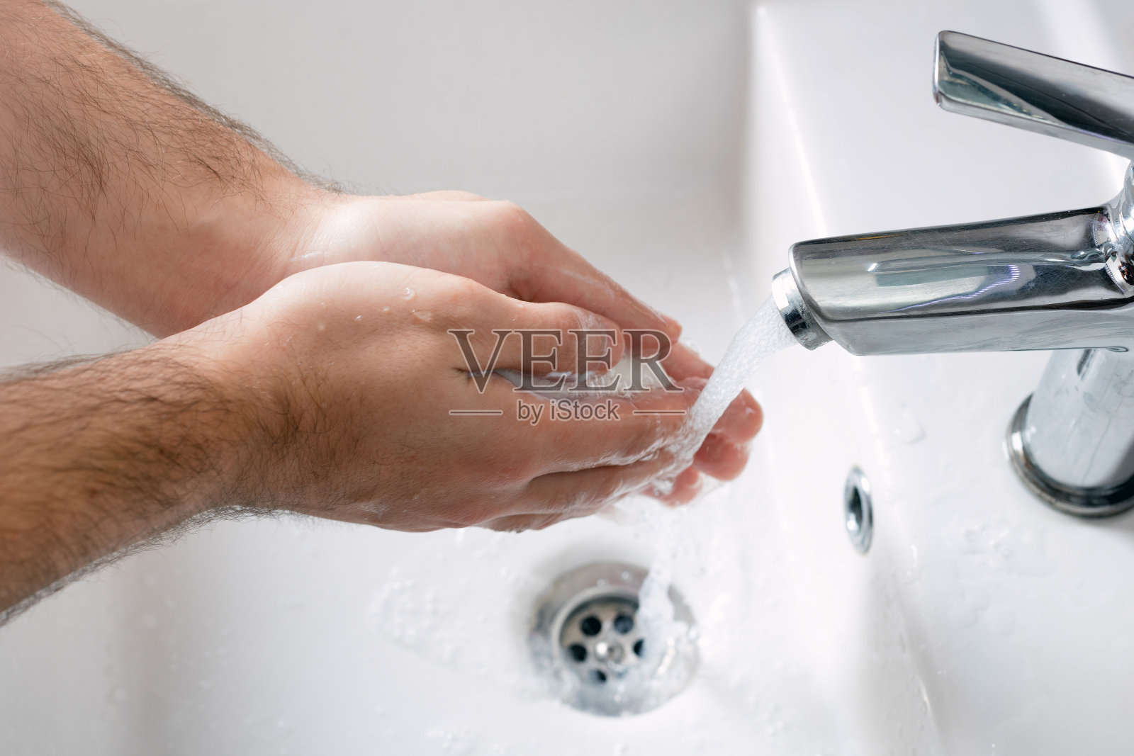 一名男子在水龙头下用自来水深深的洗手。洗手对于避免冠状病毒和细菌感染非常重要照片摄影图片