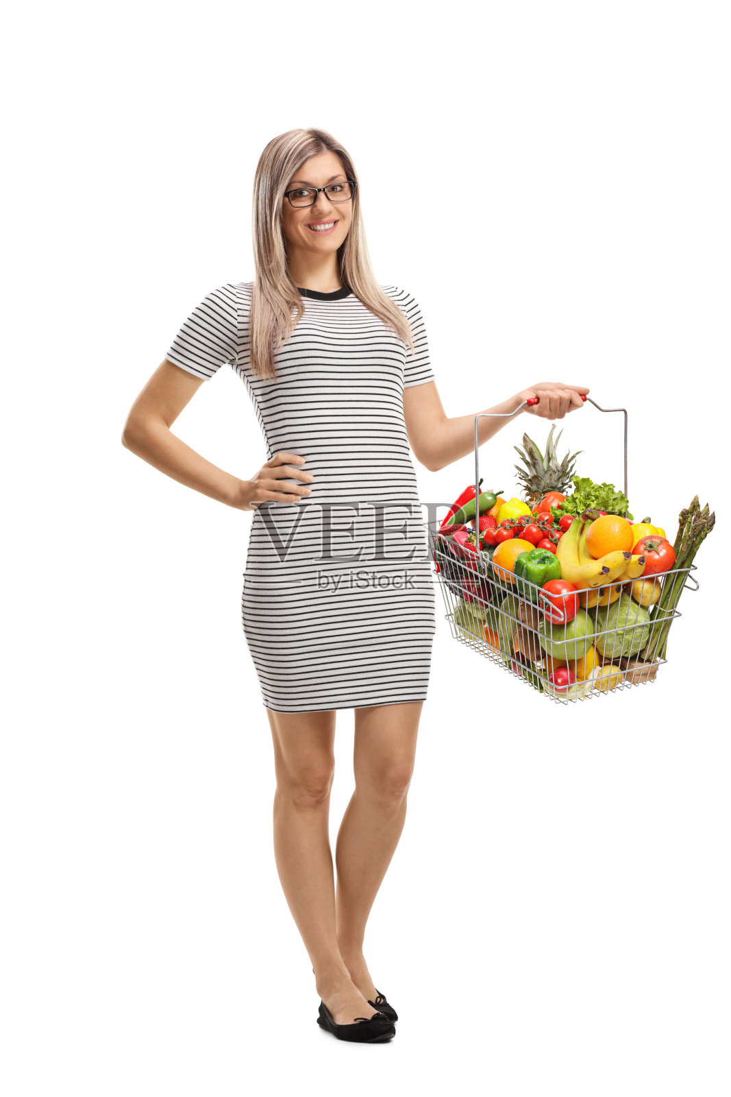 年轻女子提着一个装着新鲜水果和蔬菜的购物篮照片摄影图片