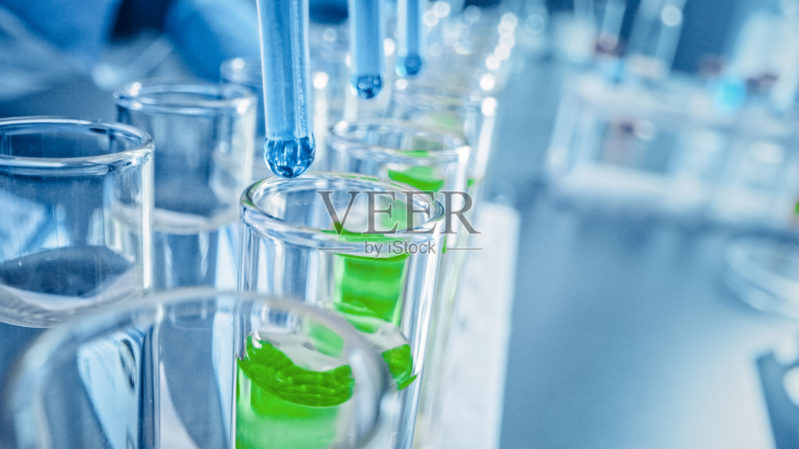 药剂学实验室:将蓝色液体滴入试管，医学研究和分析。产品线;DNA研究用滴管填充样品管。特写宏照片摄影图片