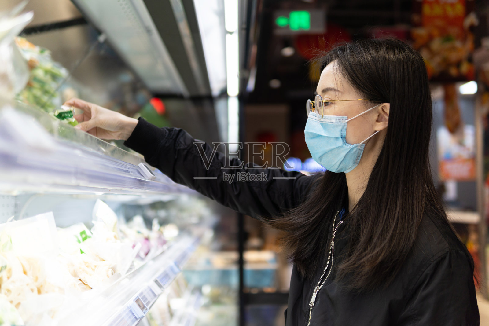 新冠肺炎疫情期间，在超市佩戴医用防护口罩的亚洲妇女。在，生活正在慢慢恢复正常。照片摄影图片
