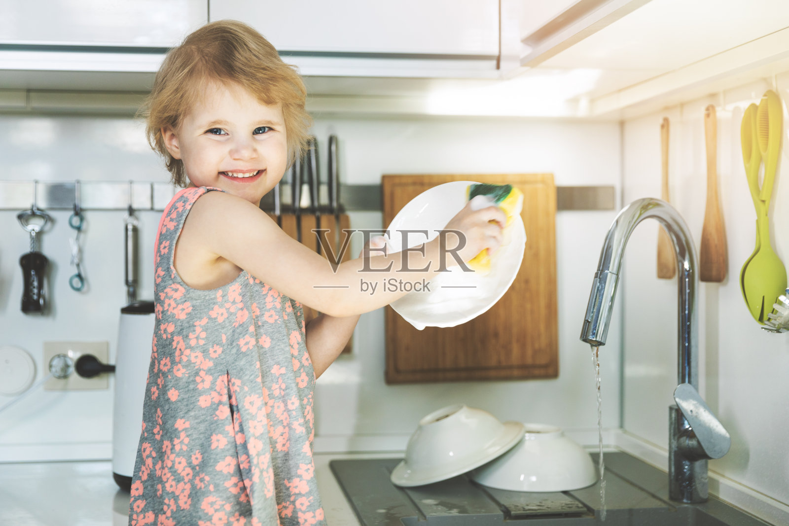 小女孩用海绵在厨房水槽里洗盘子照片摄影图片