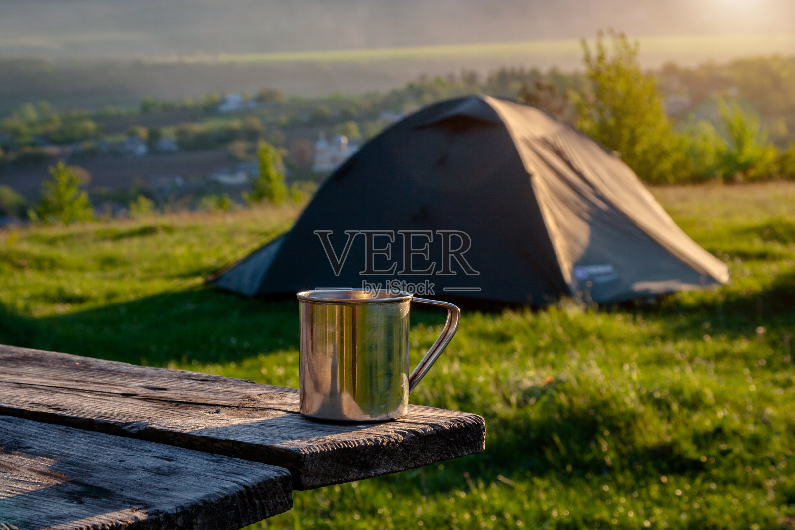 日出时，游客在绿草地上搭帐篷。照片摄影图片