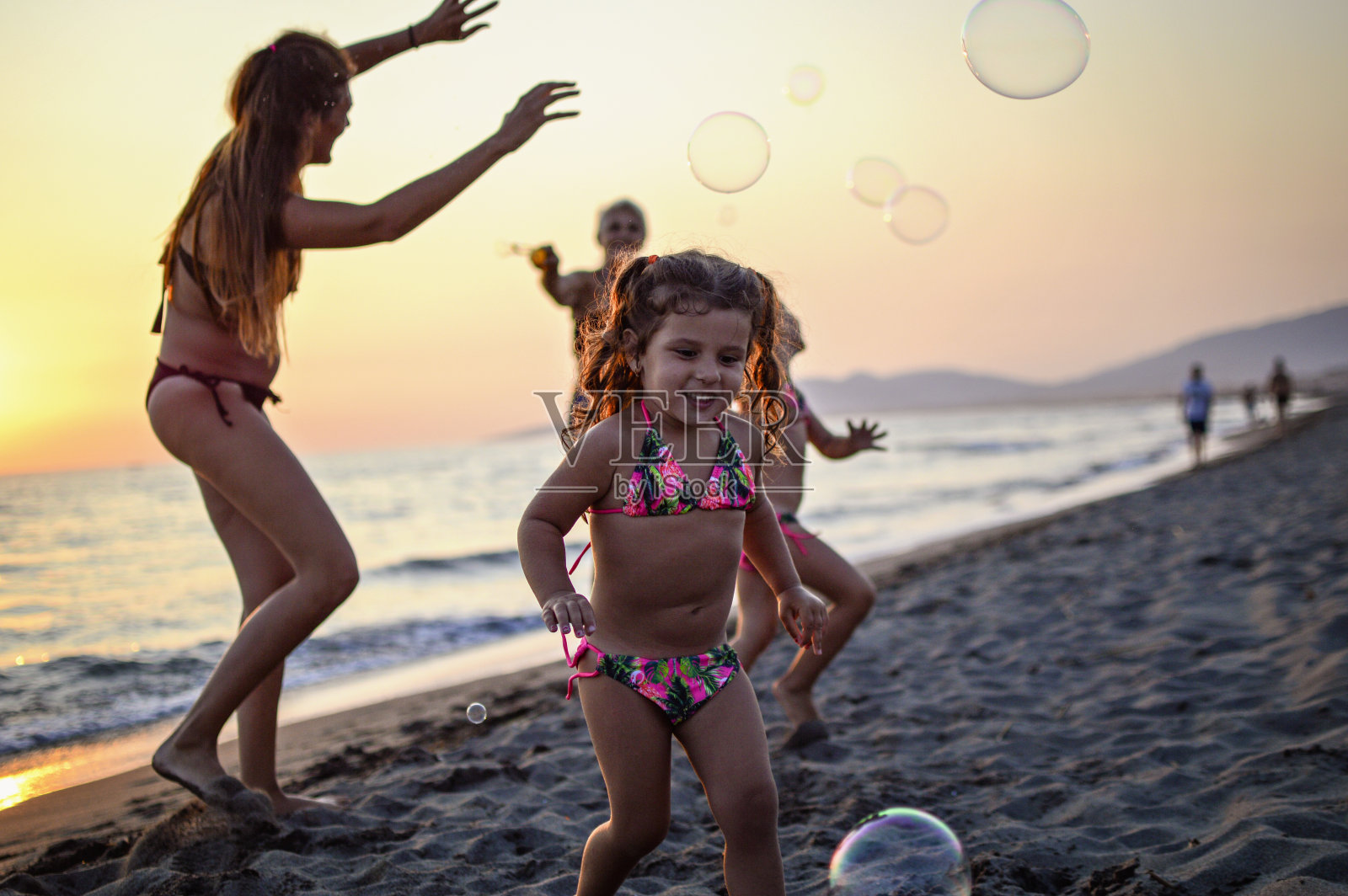 三代女人在沙滩上吹着泡泡照片摄影图片