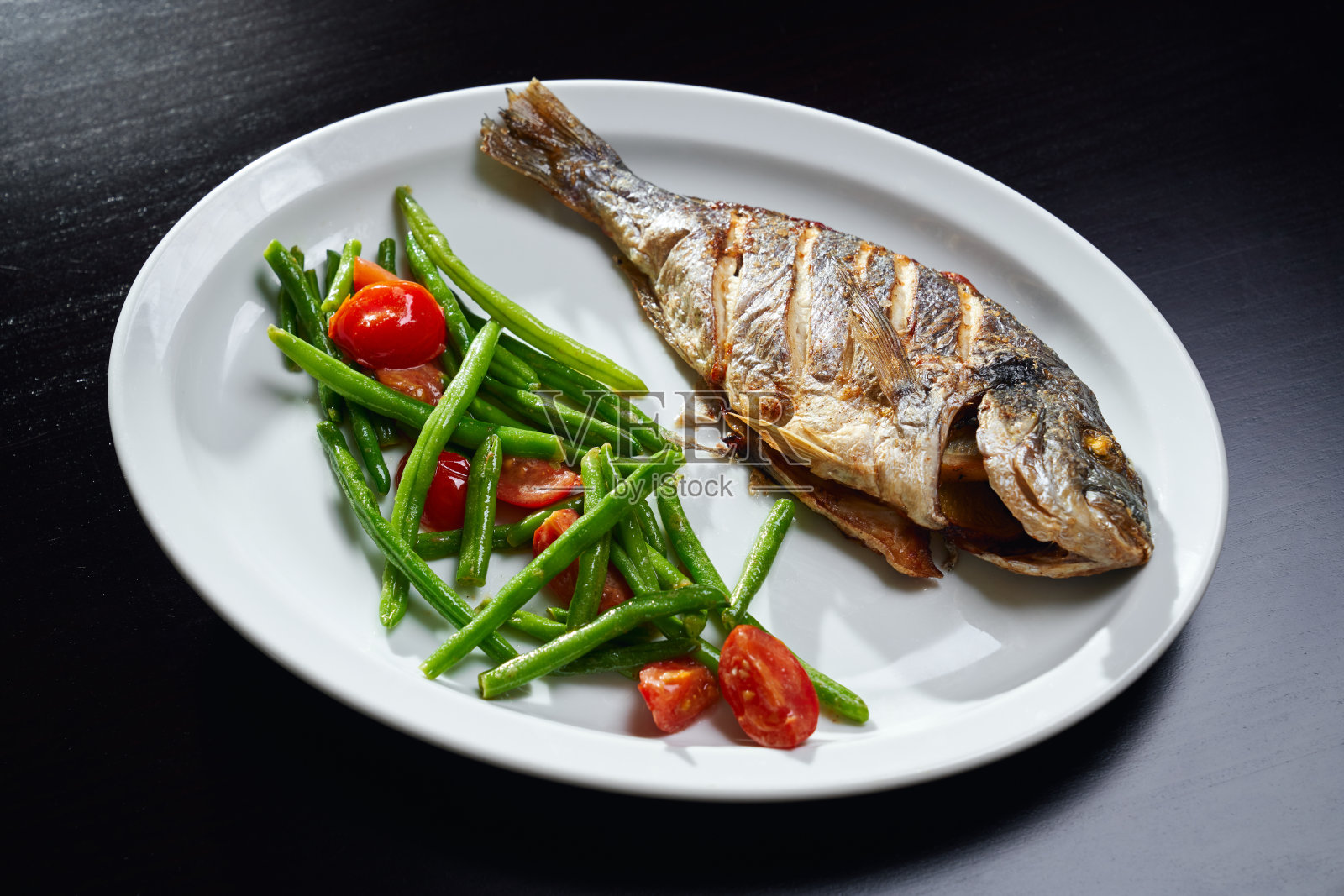 烤鲈鱼配新鲜蔬菜。照片摄影图片