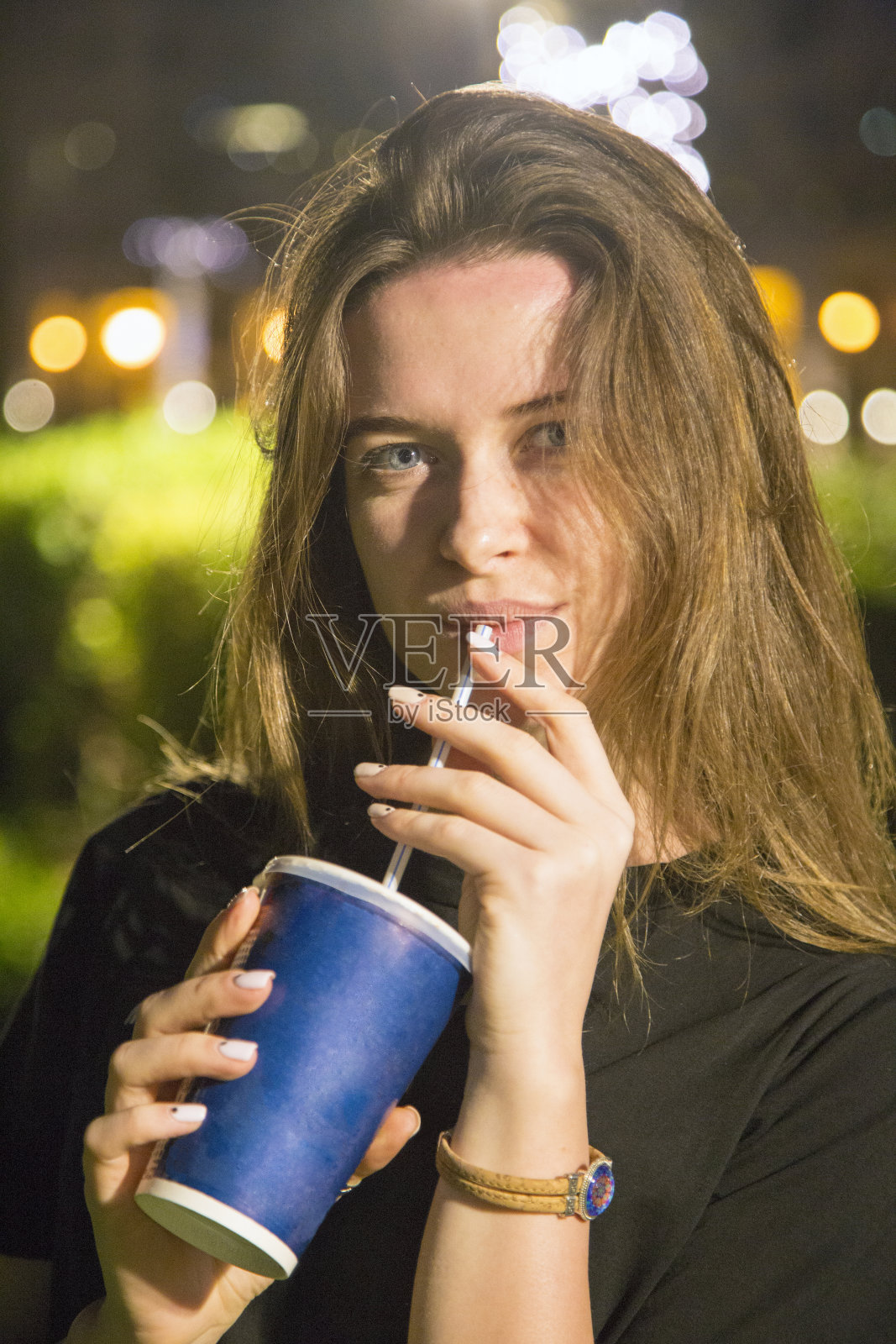 一个手里拿着酒的女孩的夜晚画像。照片摄影图片