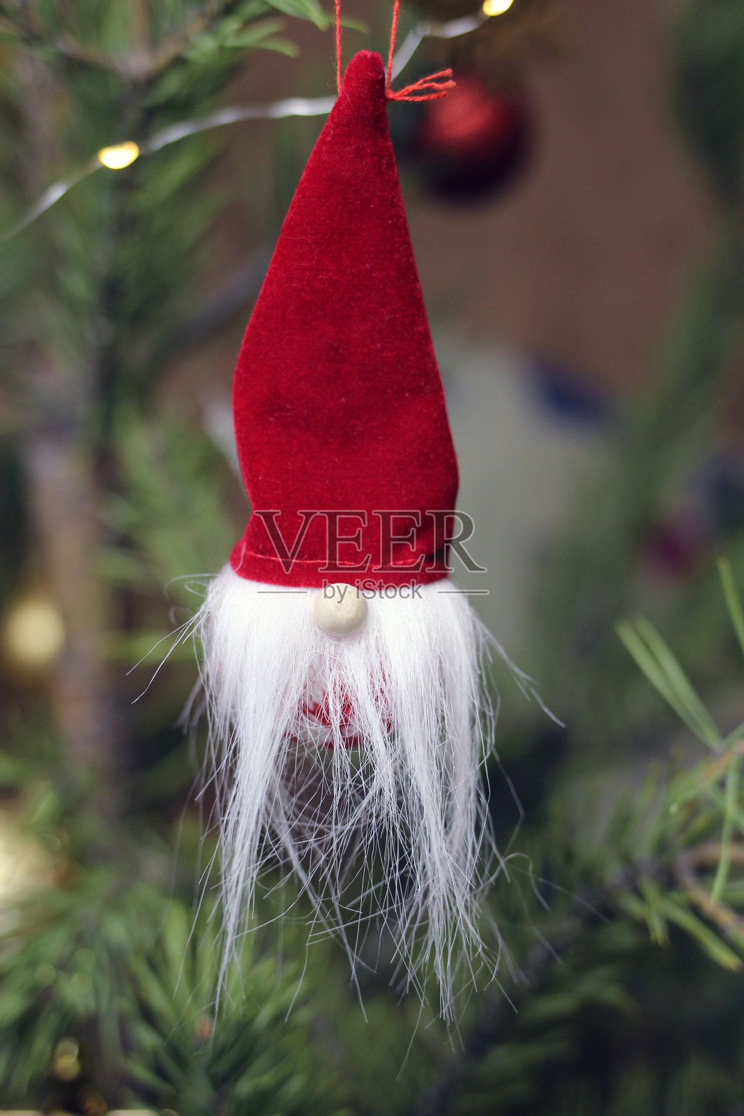 圣诞树树枝上的玩具，戴着红帽子的圣诞毛茸茸的小矮人。照片摄影图片
