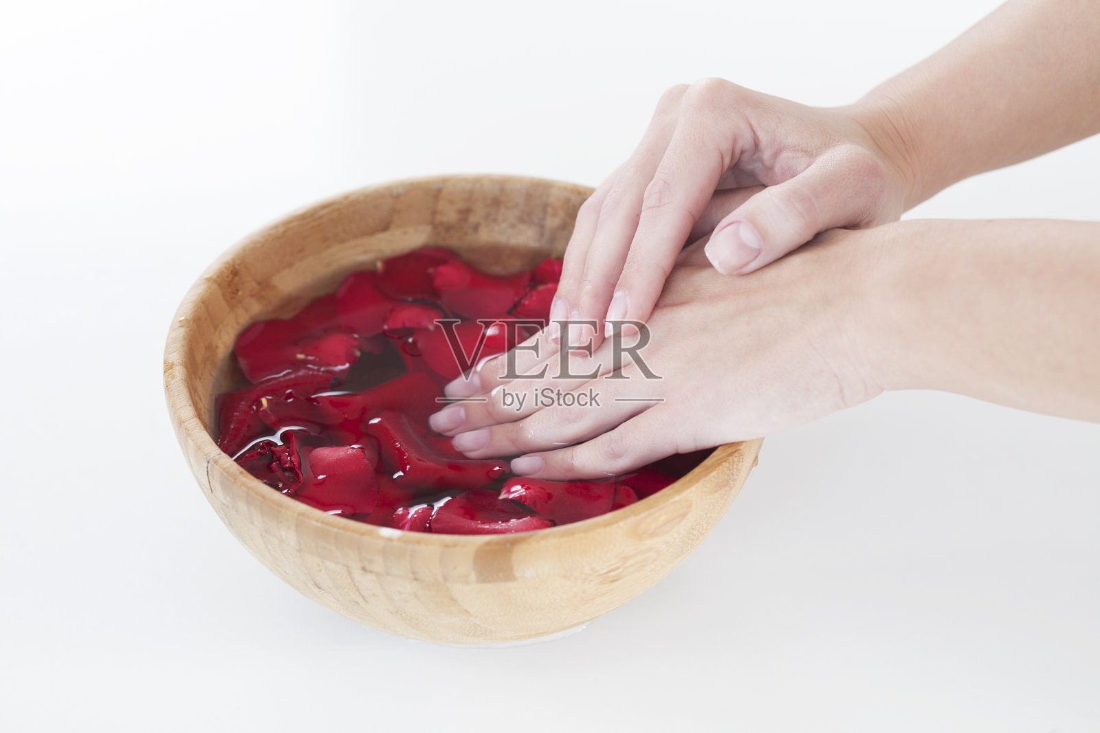 修指甲的时候，一个女人手握一个盛有水和玫瑰花瓣的碗照片摄影图片