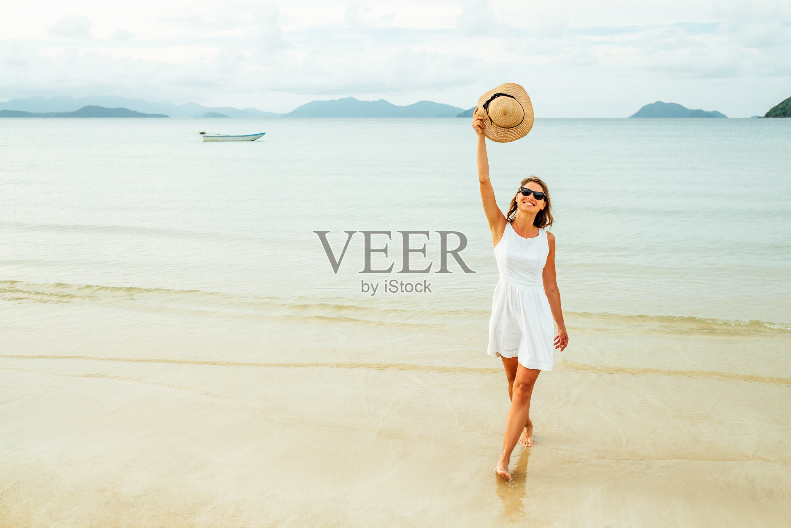 自由快乐的女人在阳光灿烂的日子里在海滩上举起双臂。幸福自由理念照片摄影图片