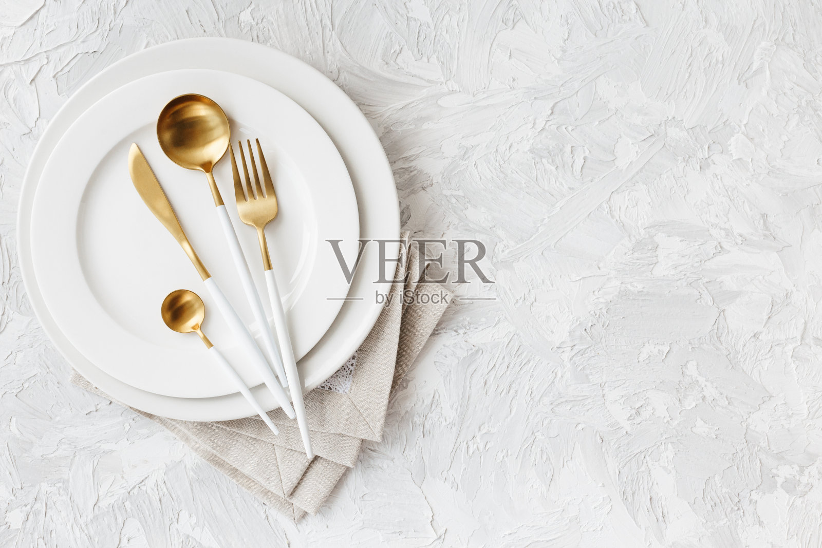 美丽的金色和白色餐具在白色的盘子上，浅白灰色的背景照片摄影图片