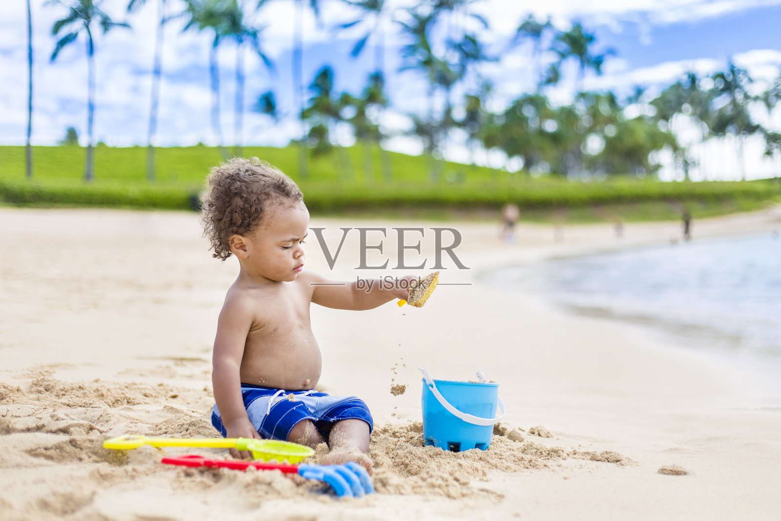 可爱的混血小男孩在热带海滩度假的沙滩上玩耍照片摄影图片
