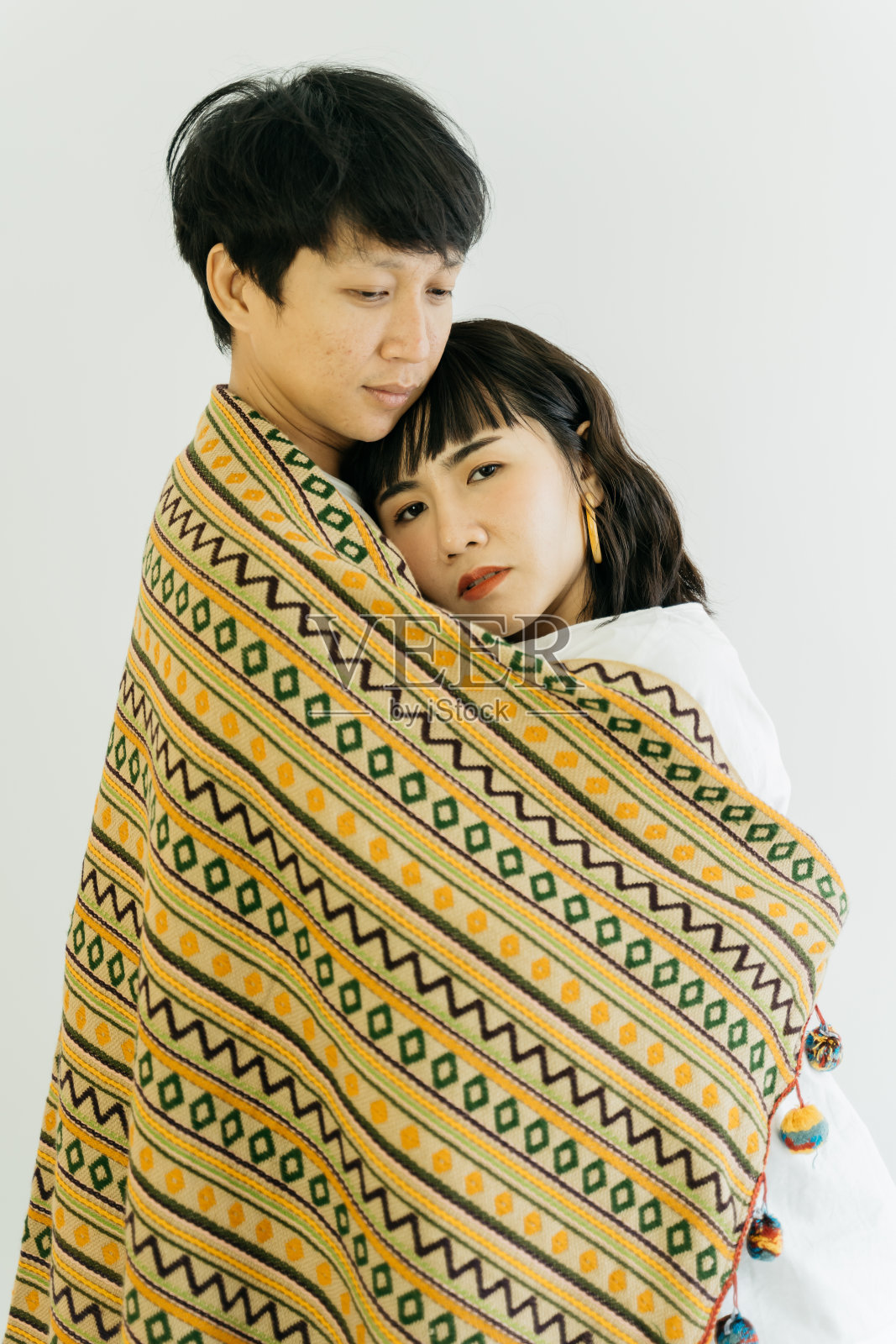这是一对可爱的亚洲夫妇裹在毯子里，拥抱在一起，在白色的背景下与世隔绝。照片摄影图片