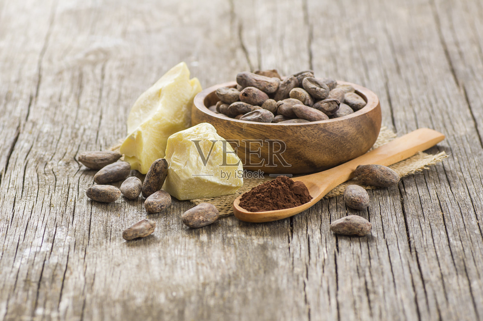 可可脂或可可豆固体油与可可粉汤匙和生可可豆在木碗在乡村背景，健康的天然油照片摄影图片