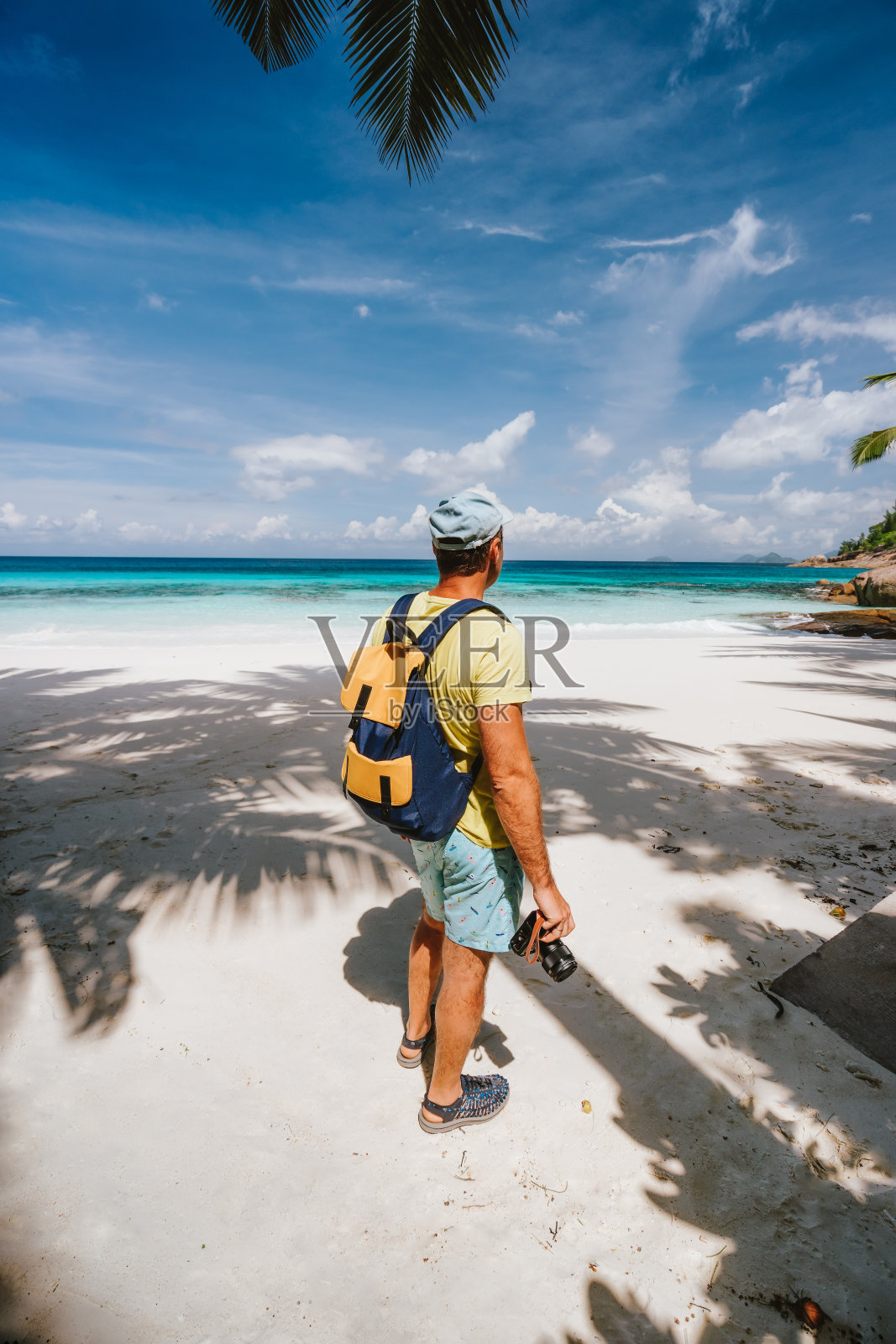 男性旅行者与相机在天堂白沙热带海滩与绿松石蓝色海洋泻湖度假假期照片摄影图片