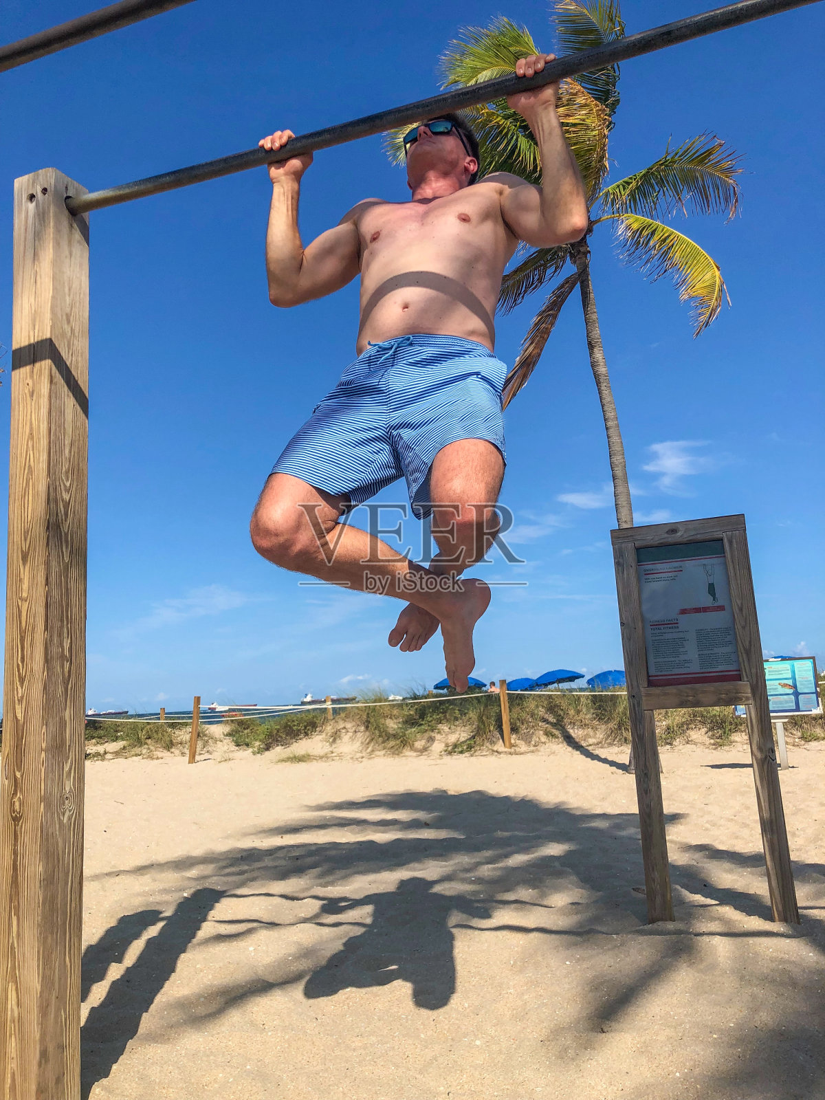在美国佛罗里达州迈阿密海滩上做引体向上的男人照片摄影图片