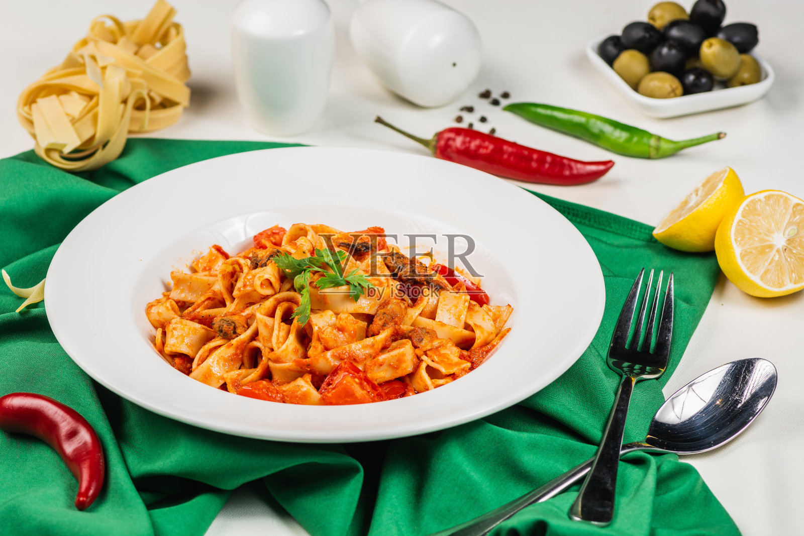 有海鲜，西红柿和香草的意大利面。装饰以罗勒，胡椒，柠檬和橄榄。意大利风格照片摄影图片