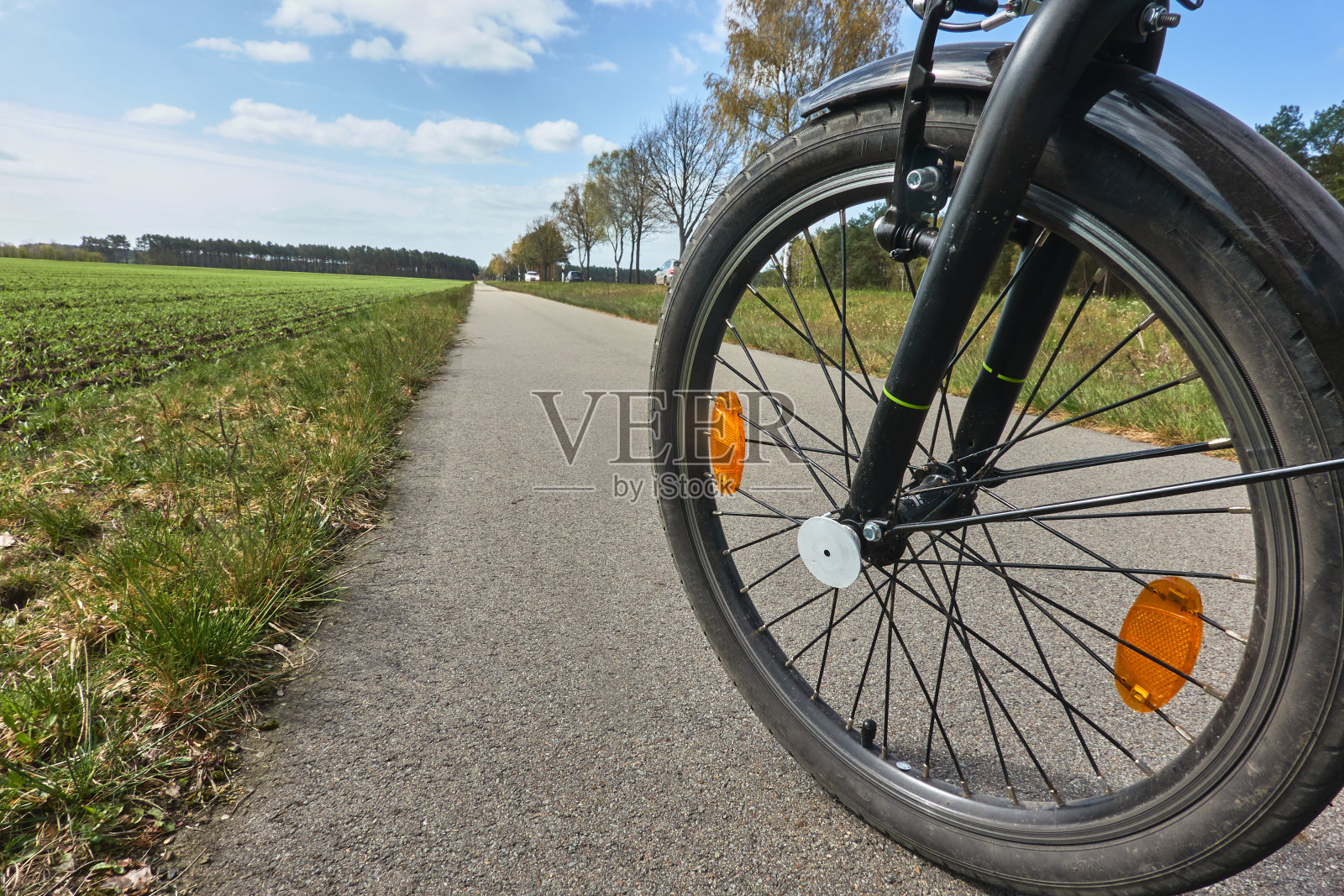 自行车的前轮在一条铺好的自行车道上，在远处的一排树旁边消失了，这是自行车旅游的概念照片照片摄影图片