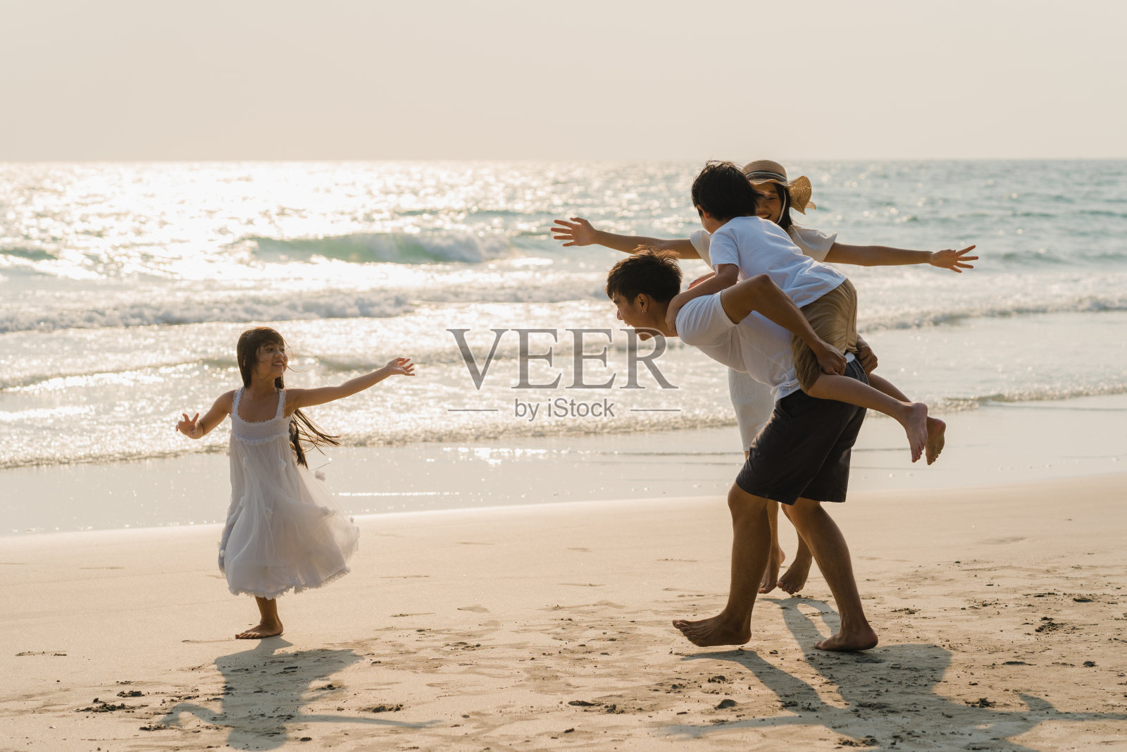 爸爸，妈妈和孩子一起放松玩海边日落时，旅游假期。照片摄影图片