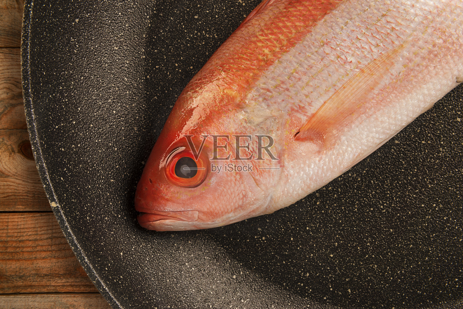 红鲷鱼生鱼孤立弃置于煎锅内。照片摄影图片