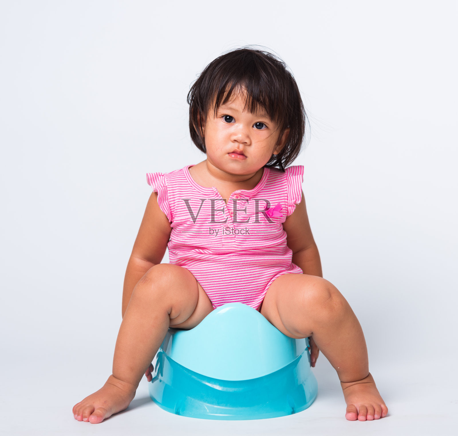 亚洲可爱的小宝贝女孩教育训练要坐在蓝色的便壶上，工作室拍摄了孤立的白色背景上的厕所概念照片摄影图片