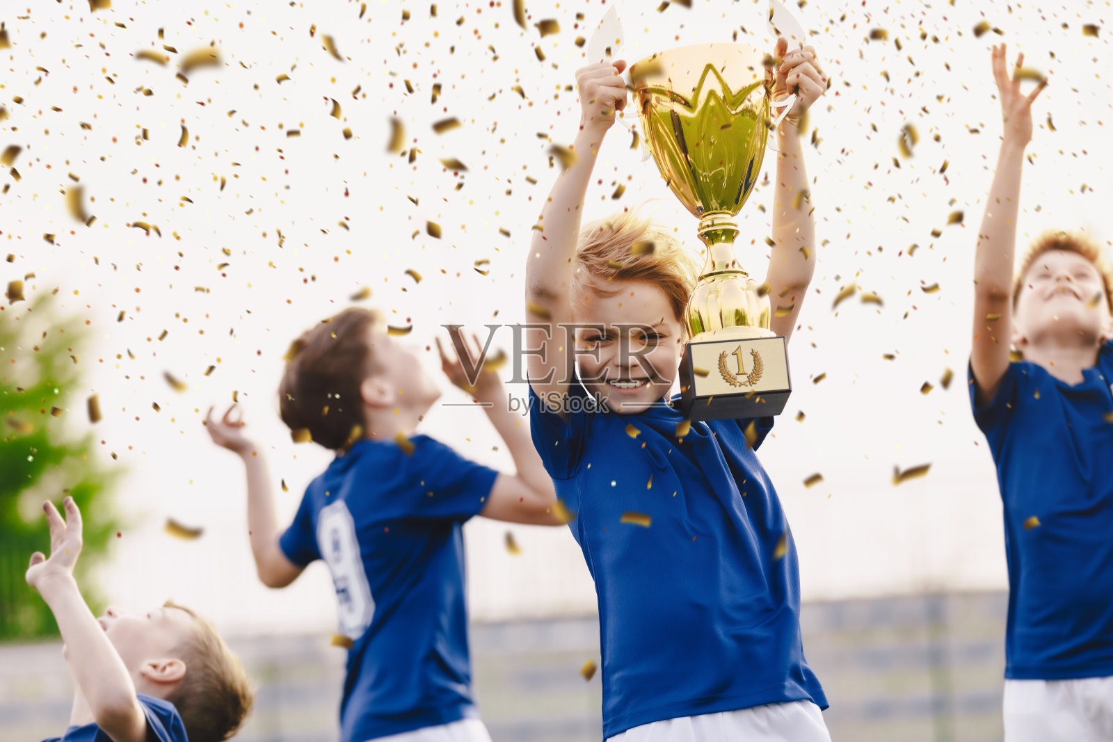 运动队庆祝胜利。快乐的男孩们举起金杯庆祝。儿童足球比赛中赢得体育比赛。校际soort竞争照片摄影图片
