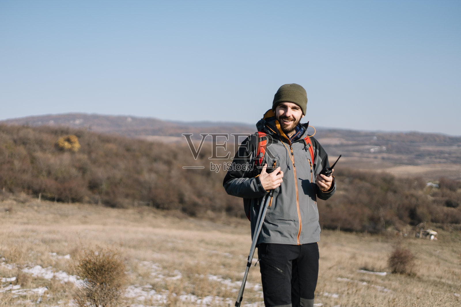 手持手杖和无线电的男性徒步者照片摄影图片
