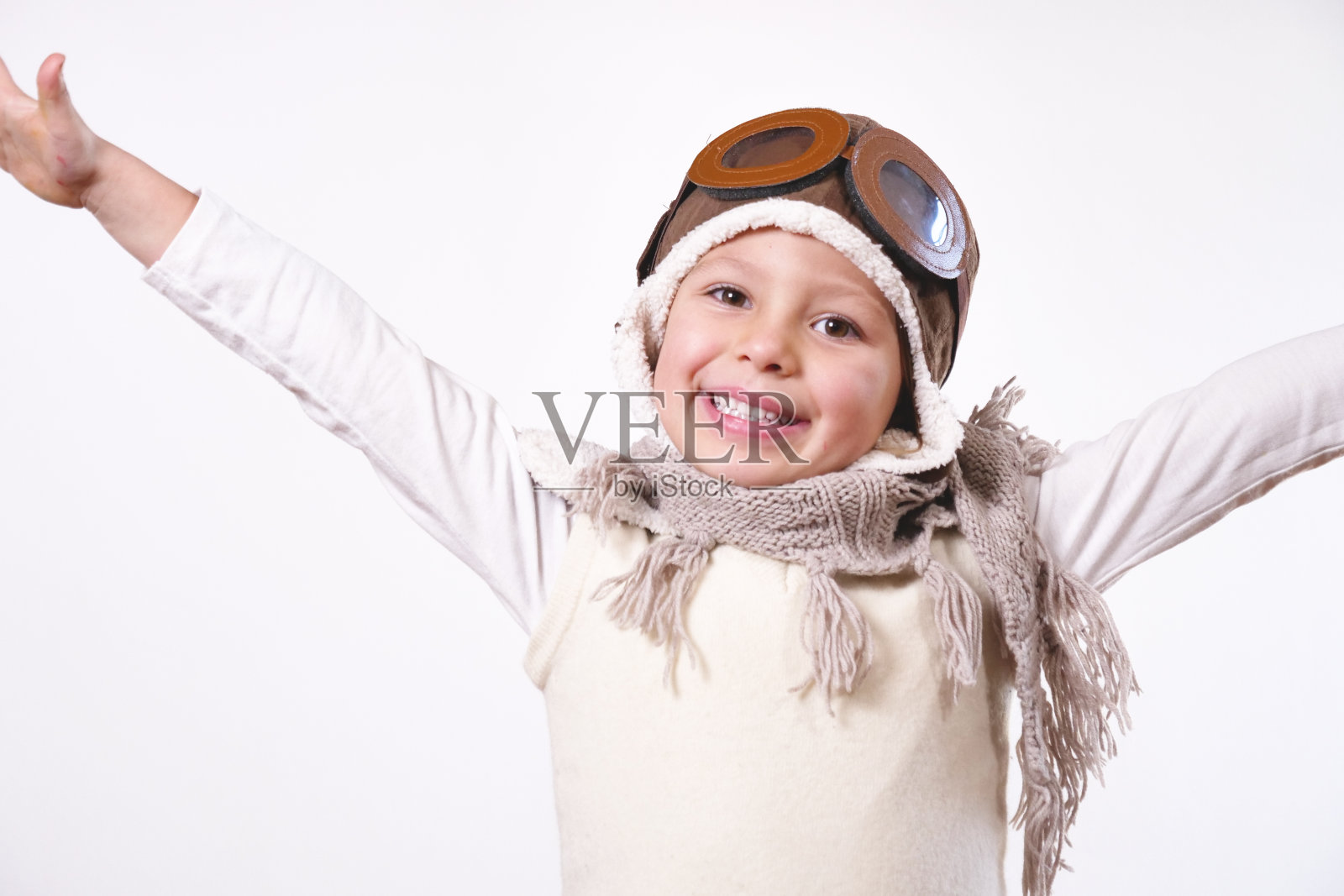 一个女孩的肖像，打扮成一个飞行员或飞行员戴着帽子和眼镜，微笑着看着相机，她睁开眼睛梦想和思考未来照片摄影图片