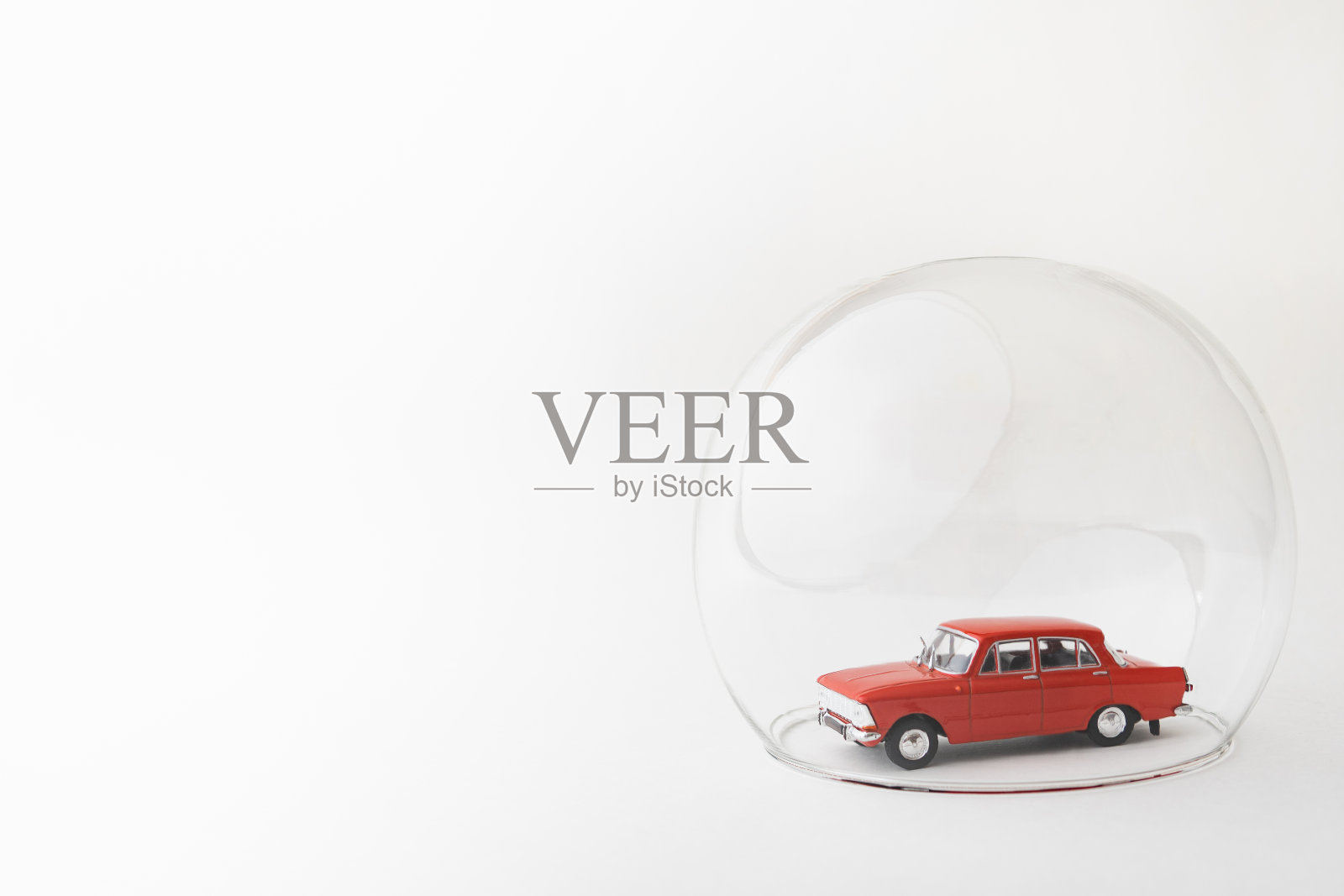红色的玩具车里装着一个玻璃球。保险范围和安全保障的概念形象照片摄影图片