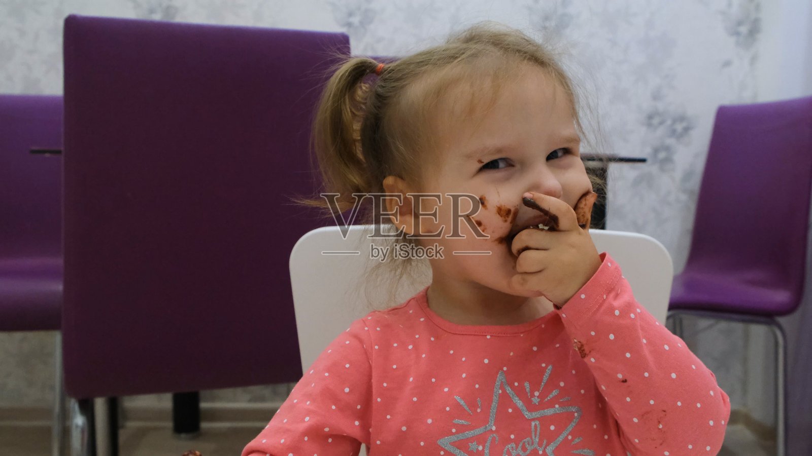 一个小女孩吃着巧克力，脸上涂满了巧克力照片摄影图片