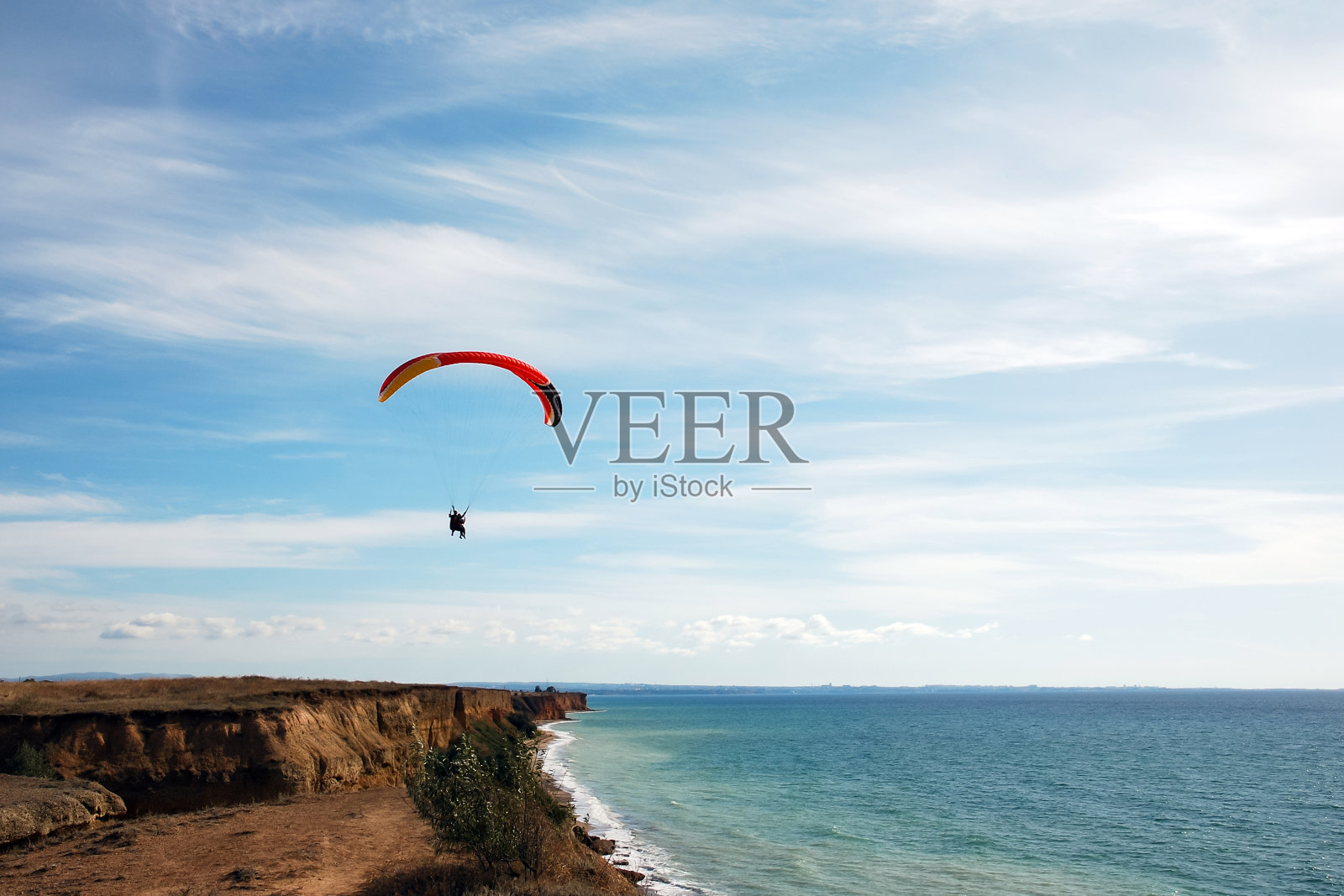 在海边的蓝天上，一串串的滑翔伞照片摄影图片