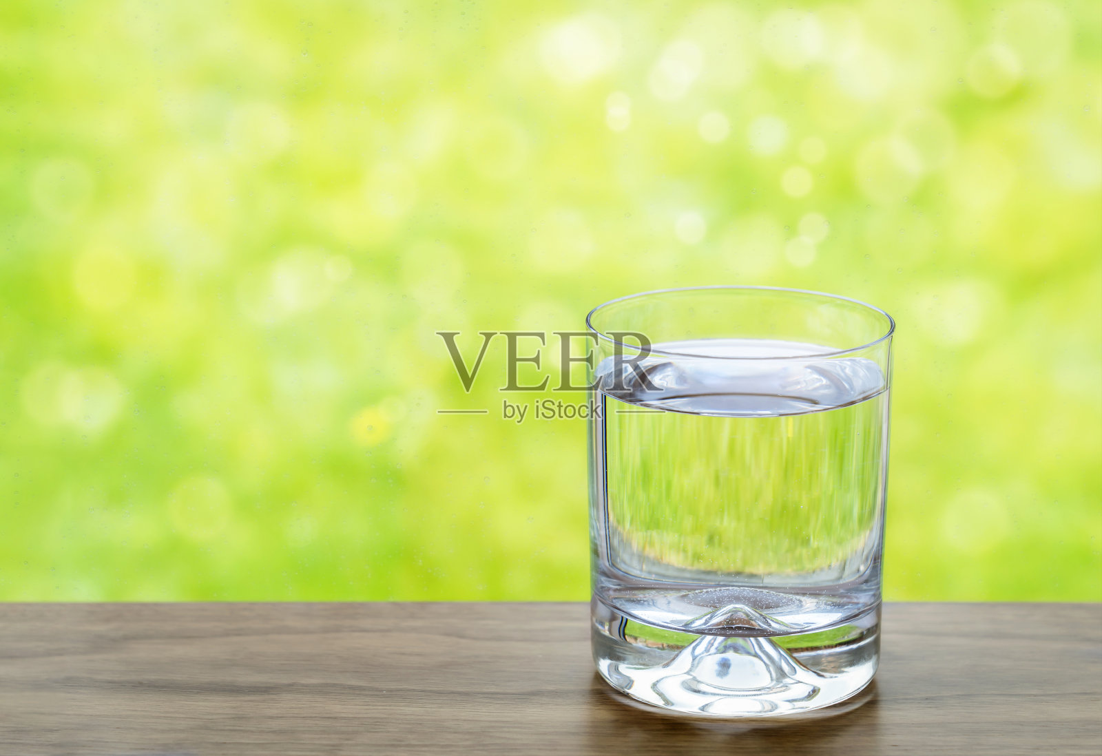 纯净的新鲜饮用水在清澈的玻璃旁边的窗户与模糊的雨滴和散景的背景。纯天然的自来水，健康的生活方式和环保理念照片摄影图片