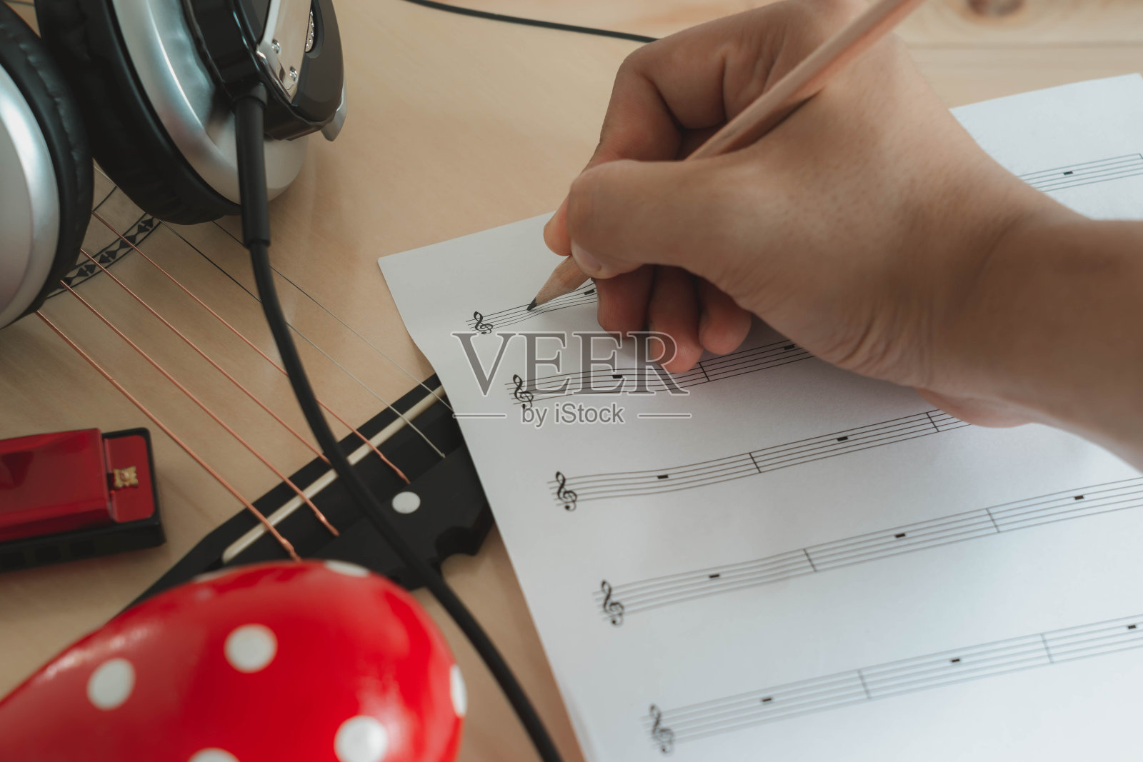乐器概念背景。近距离的音乐家在纸上写笔记创作歌曲的一组音乐工具，吉他，耳机，沙球和口琴在早上的时间。照片摄影图片