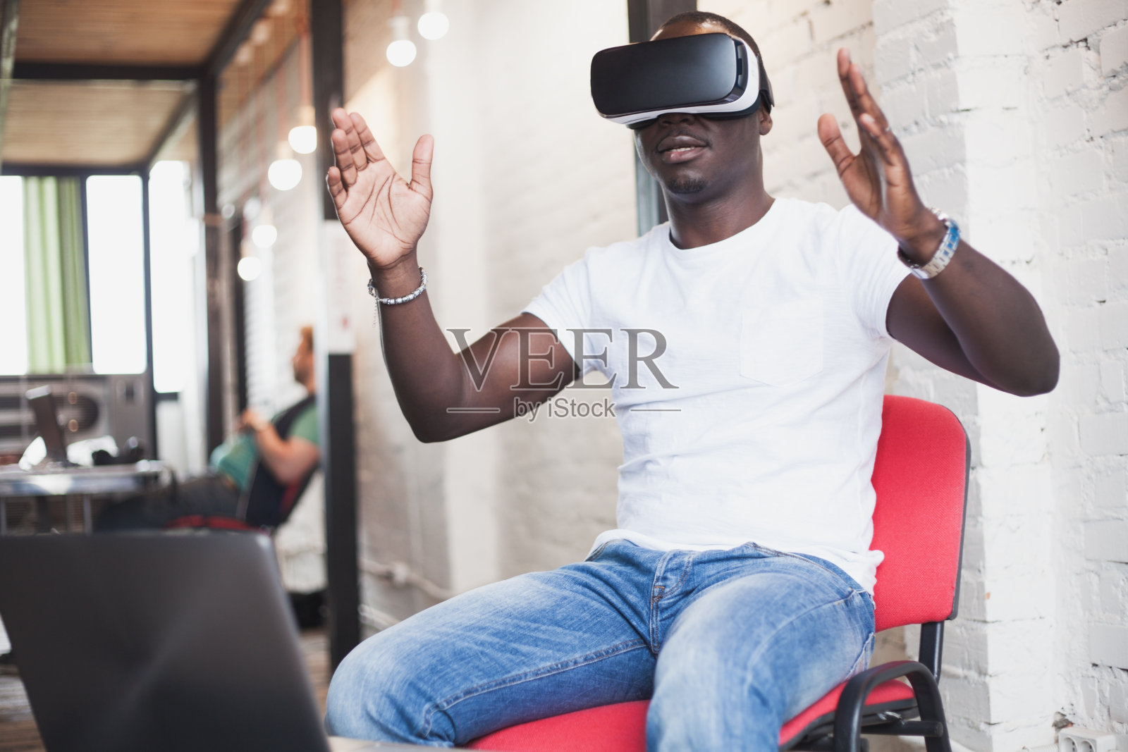 年轻人戴着虚拟现实眼镜在现代室内设计工作室。智能手机使用与VR眼镜耳机照片摄影图片