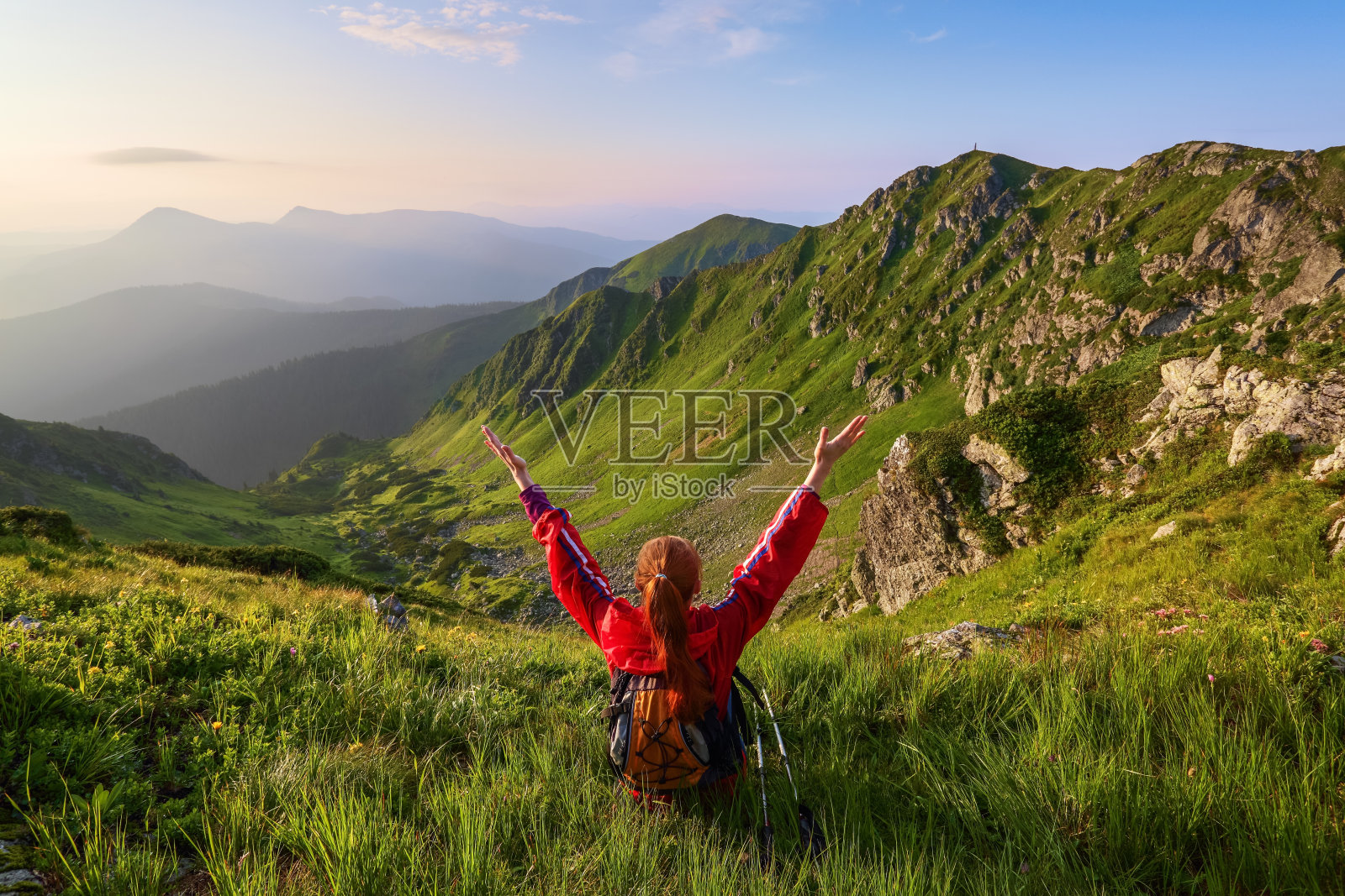带着背包和跟踪棒的女游客坐在草坪上。放松。山的风景。美好的夏日。风景。照片摄影图片