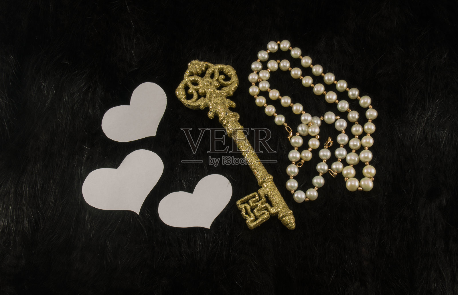 老金钥匙与白纸心和珍珠项链上的黑色毛皮背景照片摄影图片