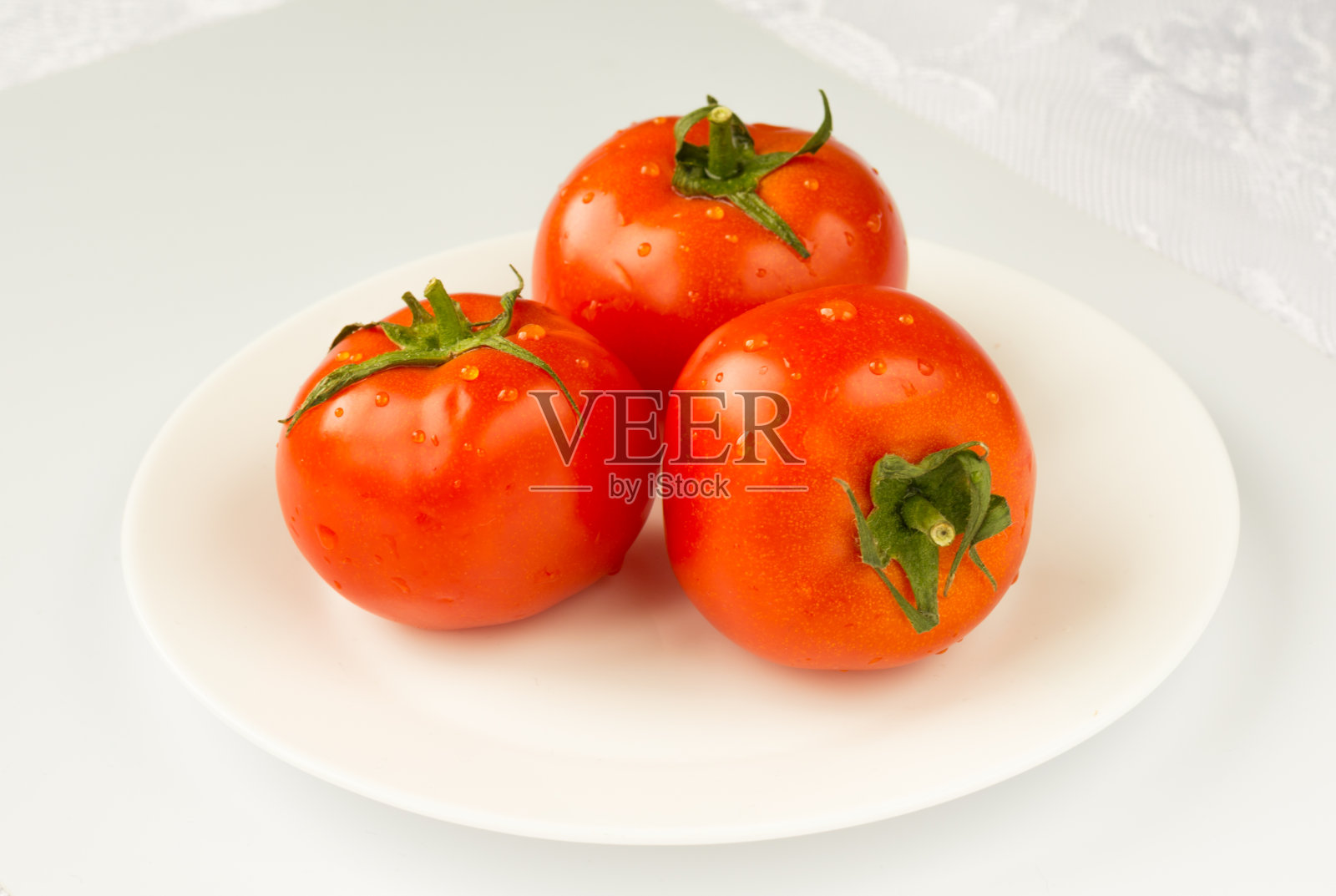 一个成熟的红番茄，在白色的背景上有孤立的水滴。照片摄影图片