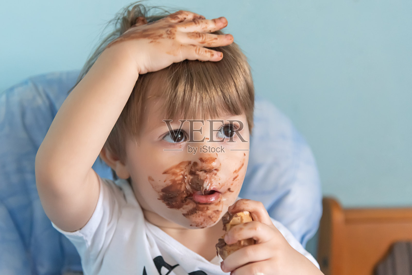 小男孩脸上涂着巧克力冰淇淋。小男孩在吃冰淇淋照片摄影图片