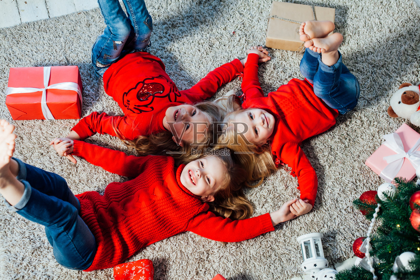 三个小女孩躺在圣诞树旁，带着新年礼物照片摄影图片