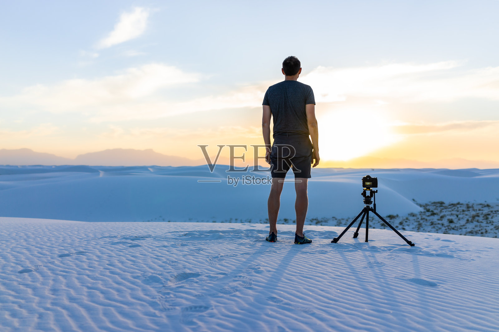 年轻的男子专业摄影师与相机三脚架拍摄时间的摄影在白沙沙丘国家纪念碑，新墨西哥日落与瀑山的观点照片摄影图片