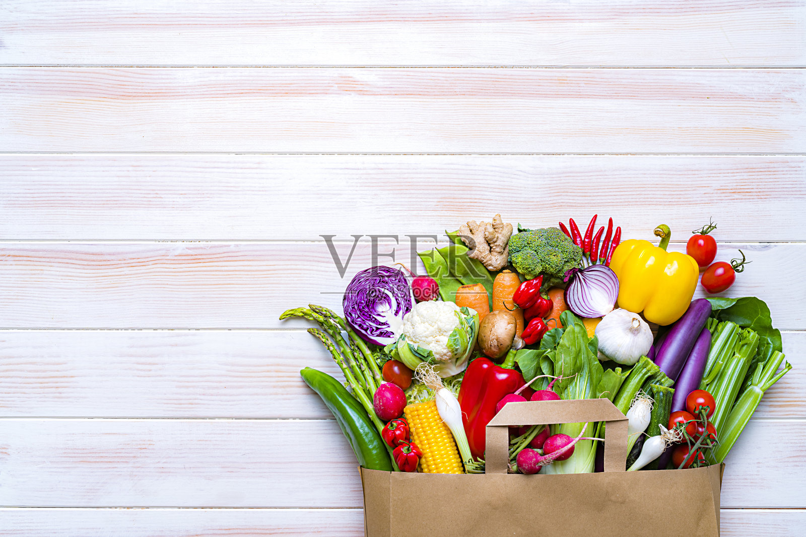 白色的桌子上放着装满新鲜有机蔬菜的购物袋。本空间照片摄影图片