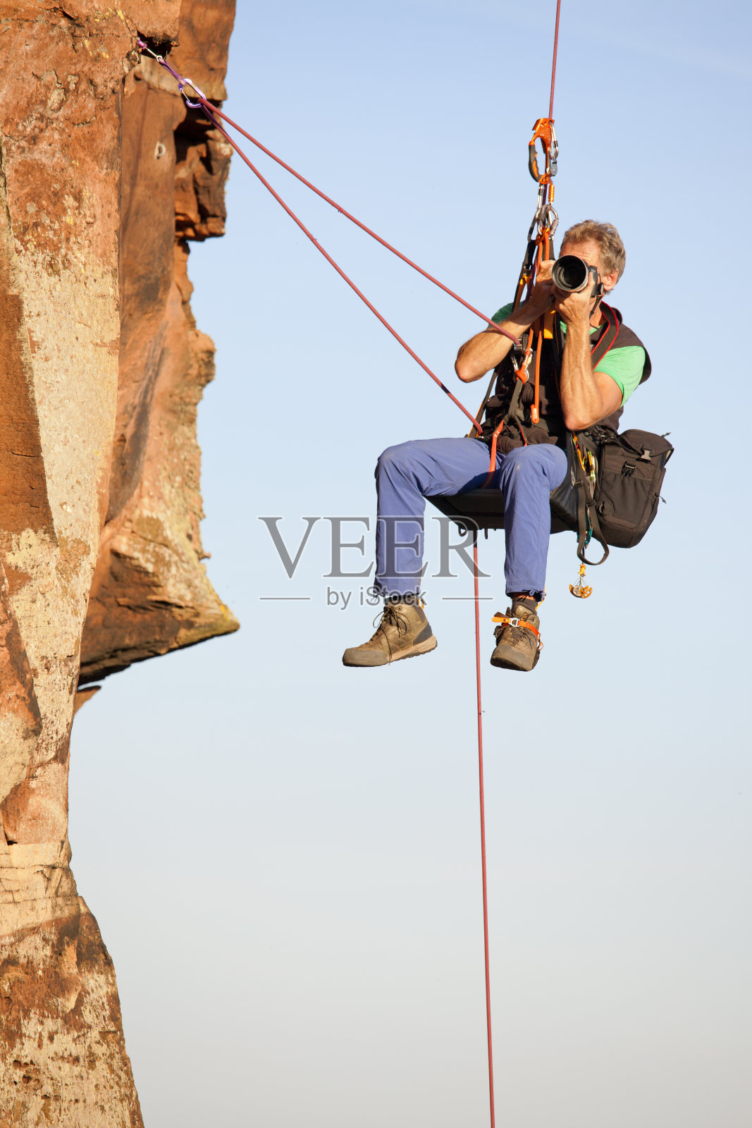 摄影师和攀岩者诺伯特·弗兰克挂在岩石前拍照照片摄影图片
