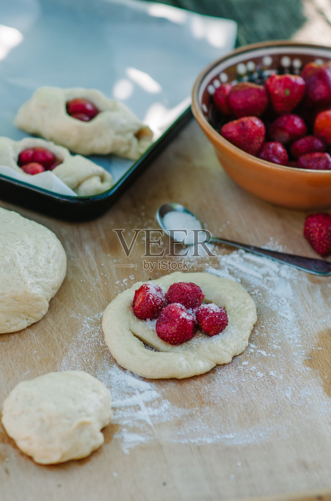 女人烤草莓面包。面团放在桌上。揉面团。照片摄影图片