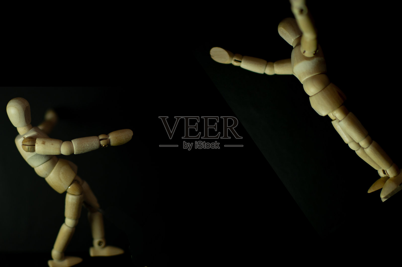 木制人体模型在黑色背景上跳跃和拥抱照片摄影图片