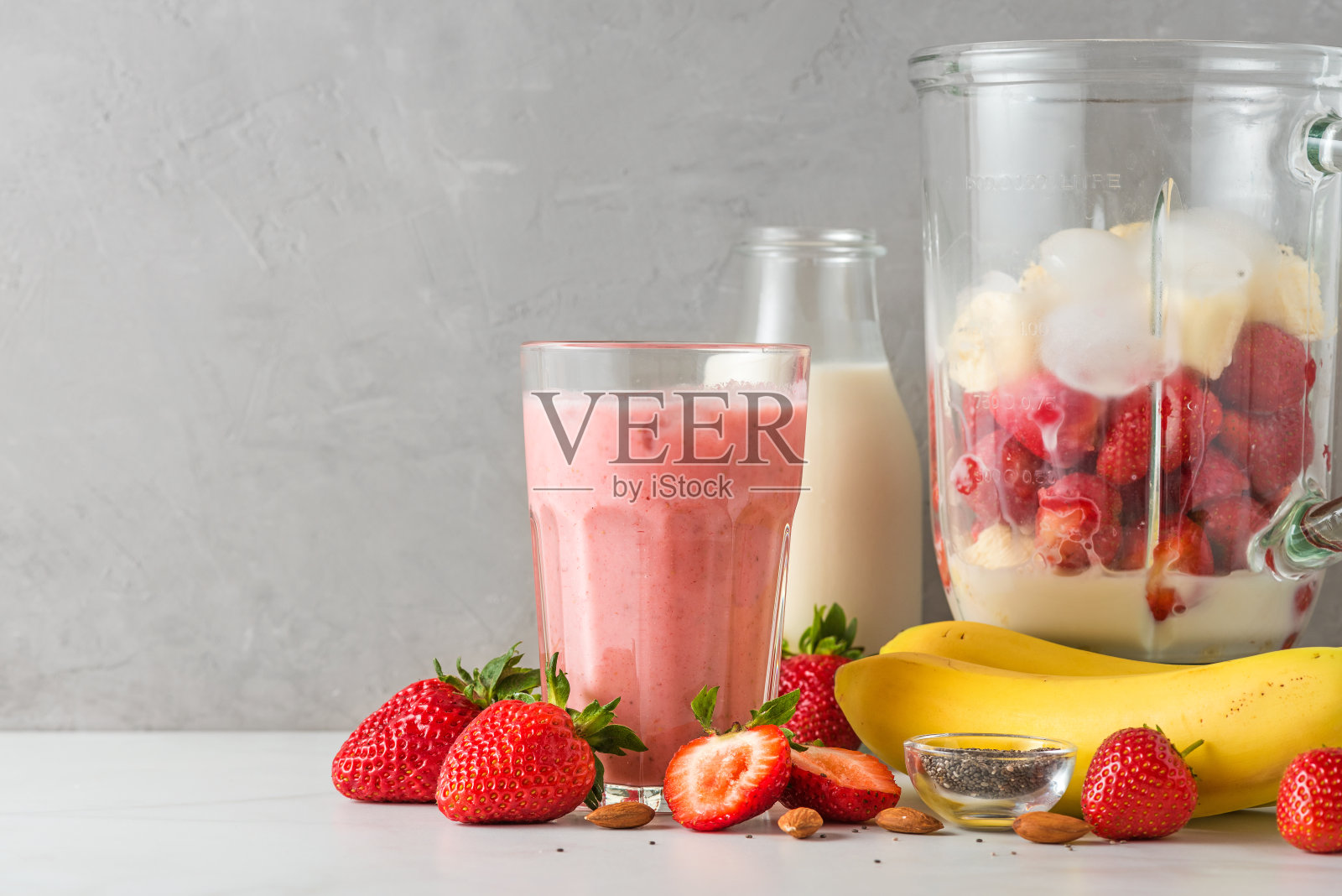 将新鲜多汁的草莓香蕉冰沙或奶昔放入搅拌机，制成健康饮料照片摄影图片