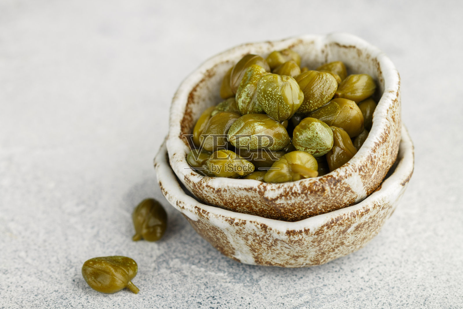 腌制或盐腌酸豆在陶瓷碗特写。未开放的花蕾。地中海，意大利，西班牙，法国菜肴的美味配料。选择性聚焦，复制空间照片摄影图片
