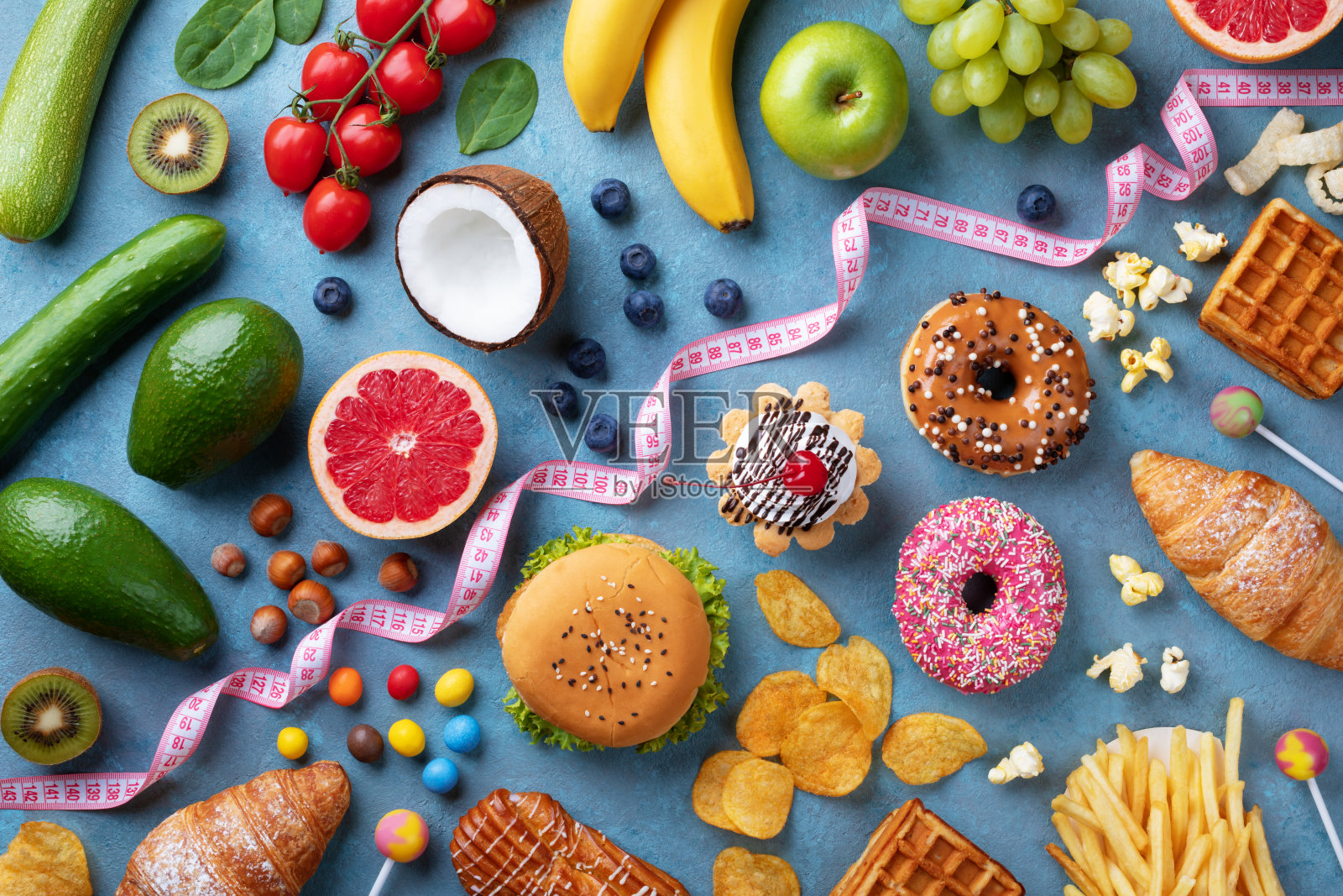 健康和不健康的食物背景从水果和蔬菜vs快餐，糖果和糕点俯视图。饮食和排毒对抗卡路里和超重的生活方式概念。照片摄影图片