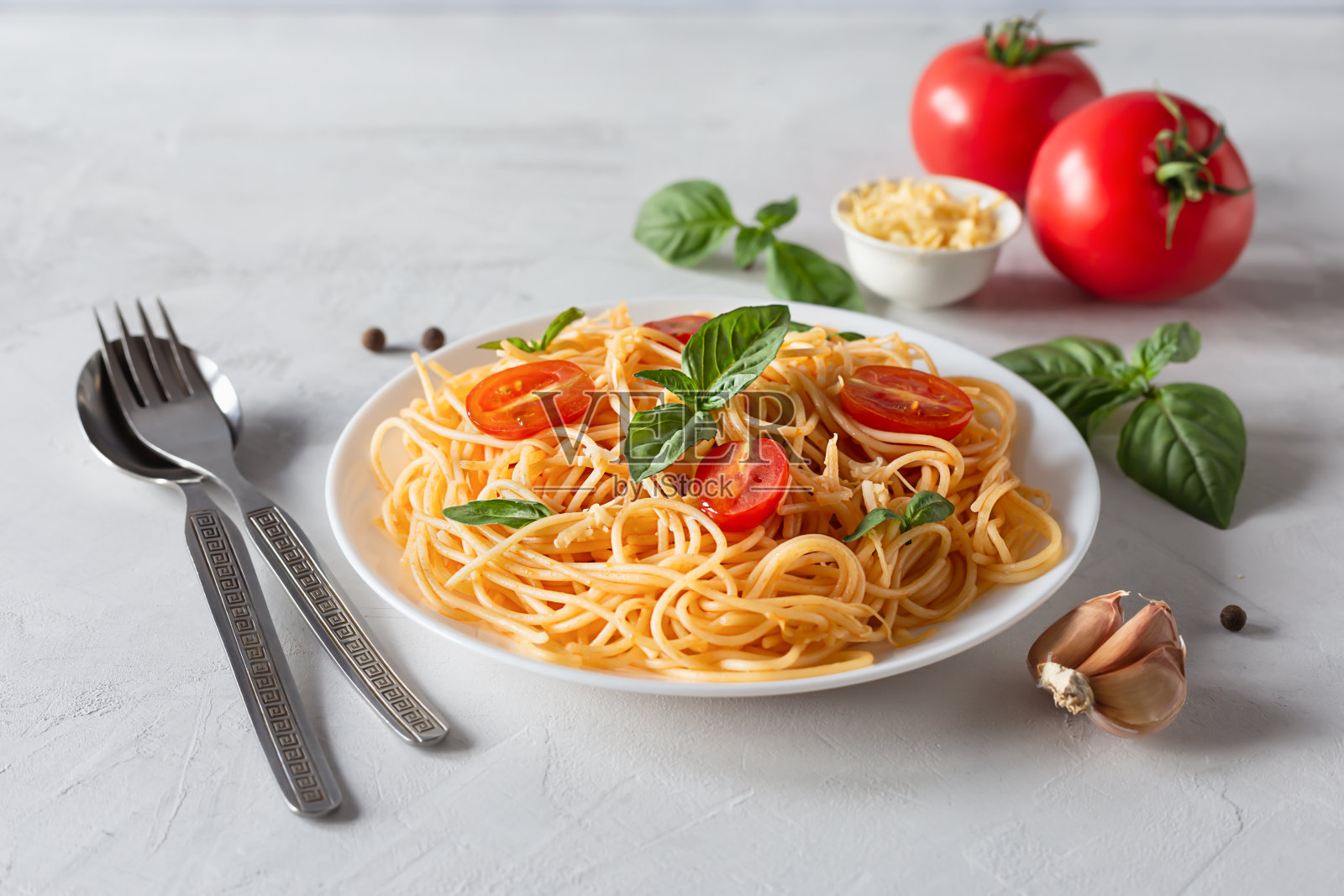 美味的意大利面，配上番茄酱，西红柿和罗勒，在灰色的背景上。意大利菜的概念照片摄影图片