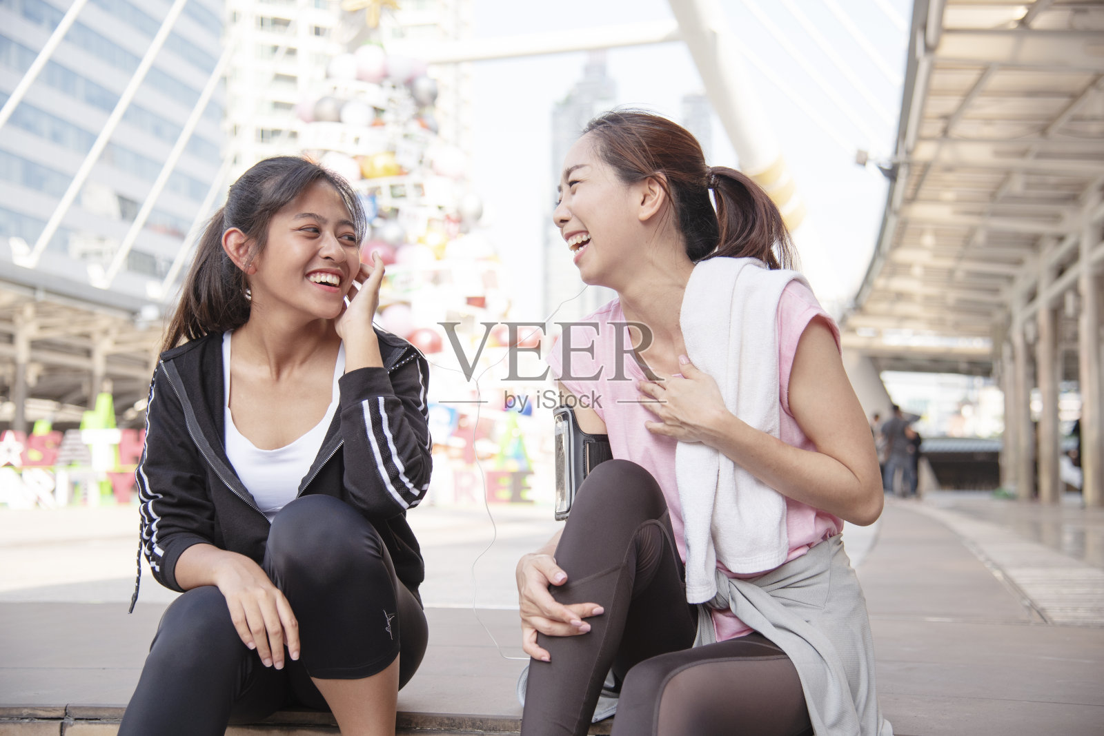 亚洲运动健身在现代城市中进行锻炼的女性在户外穿着健康运动服。年轻女子在阳光明媚的户外锻炼。健康、健康、生活方式女性概念。照片摄影图片